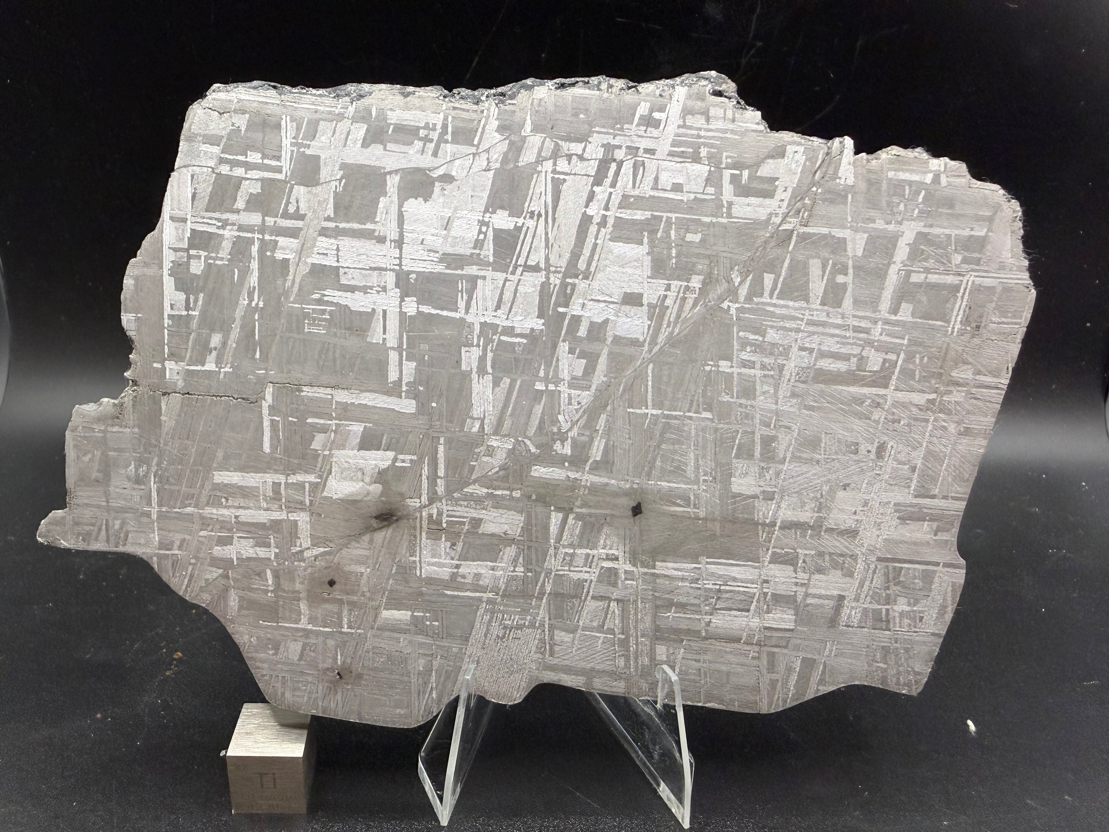 Muonionalusta IVA iron meteorite slice with etched Widmanstätten pattern, displayed on acrylic stand with 1cm scale cube