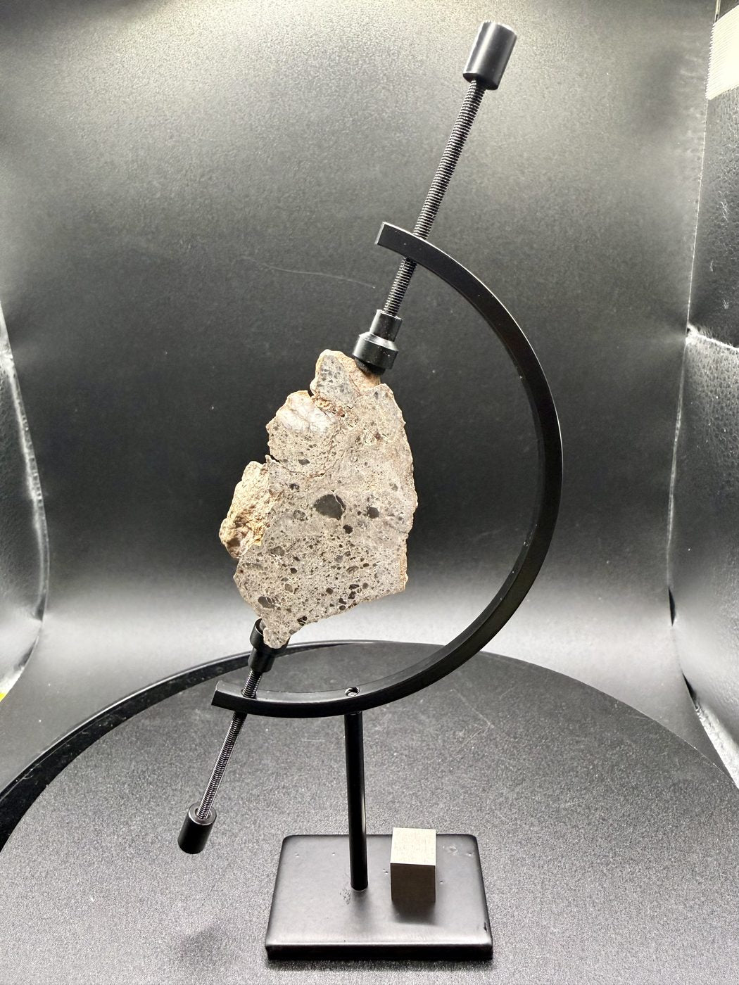 NEA 089 lunar meteorite, larger half on a display stand, exterior side forward