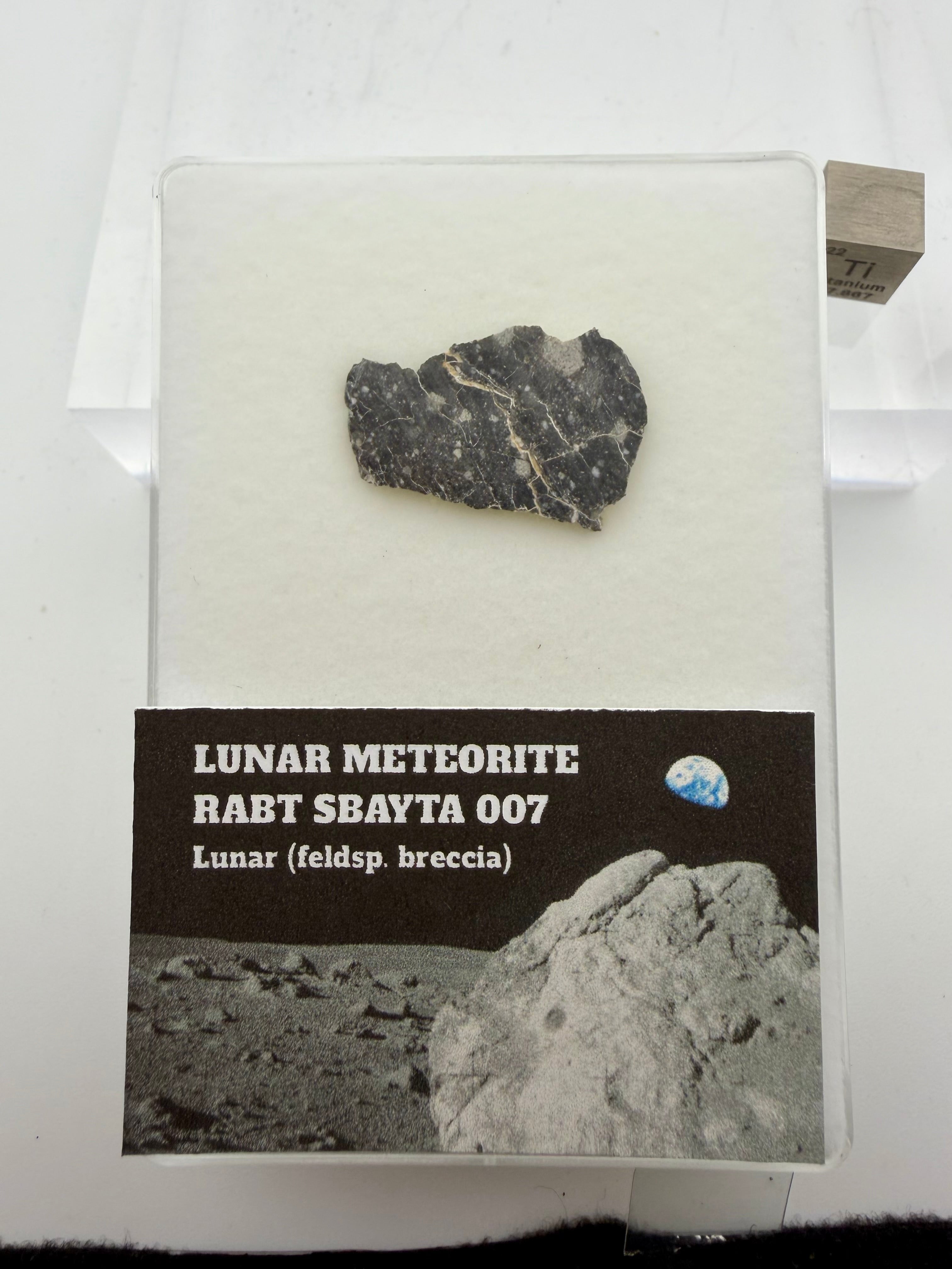 Lunar meteorite sample in a display case with text and images of the moon.