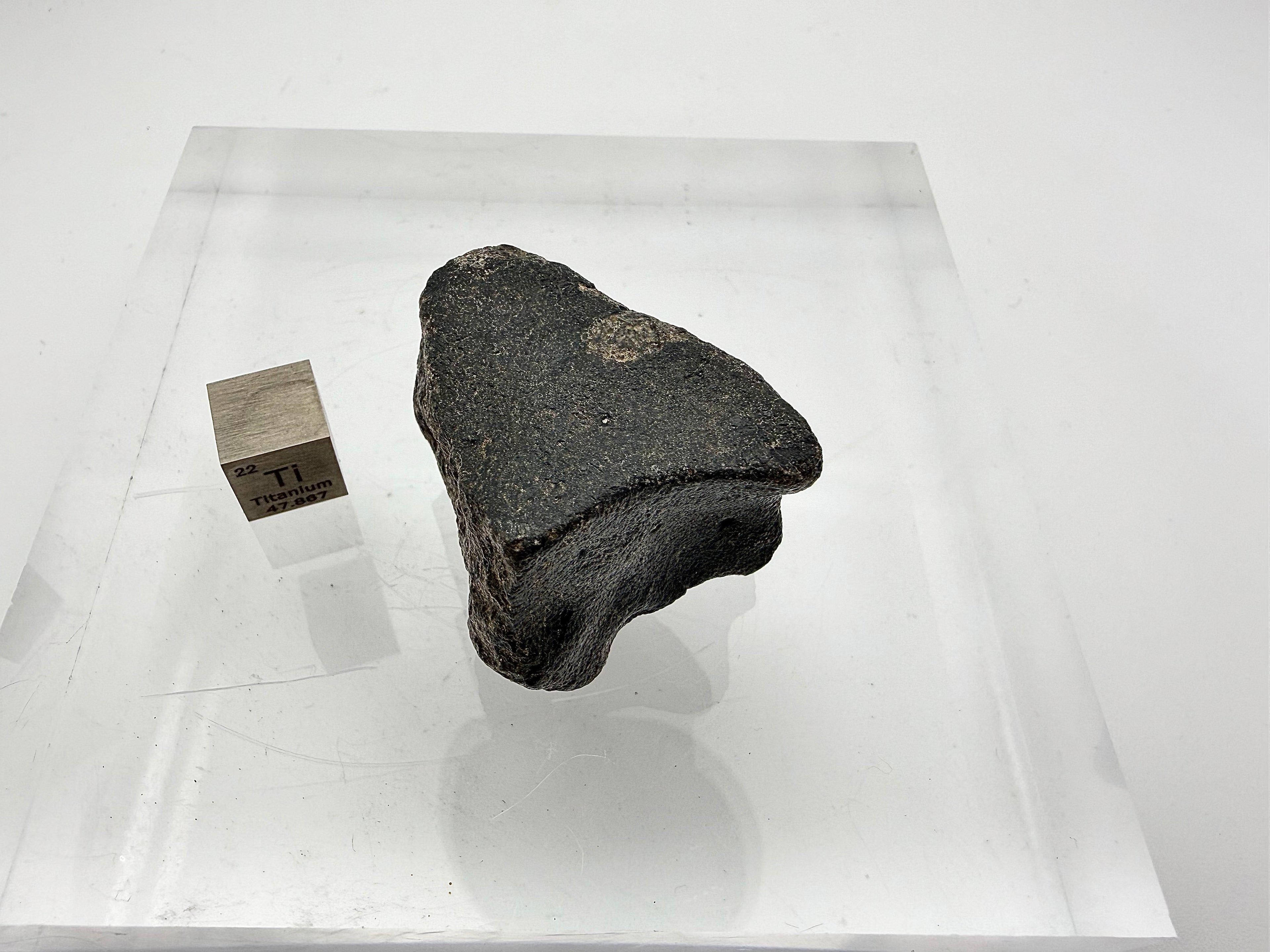 Top view of lunar mare basalt with fusion crust and orientation next to scale cube