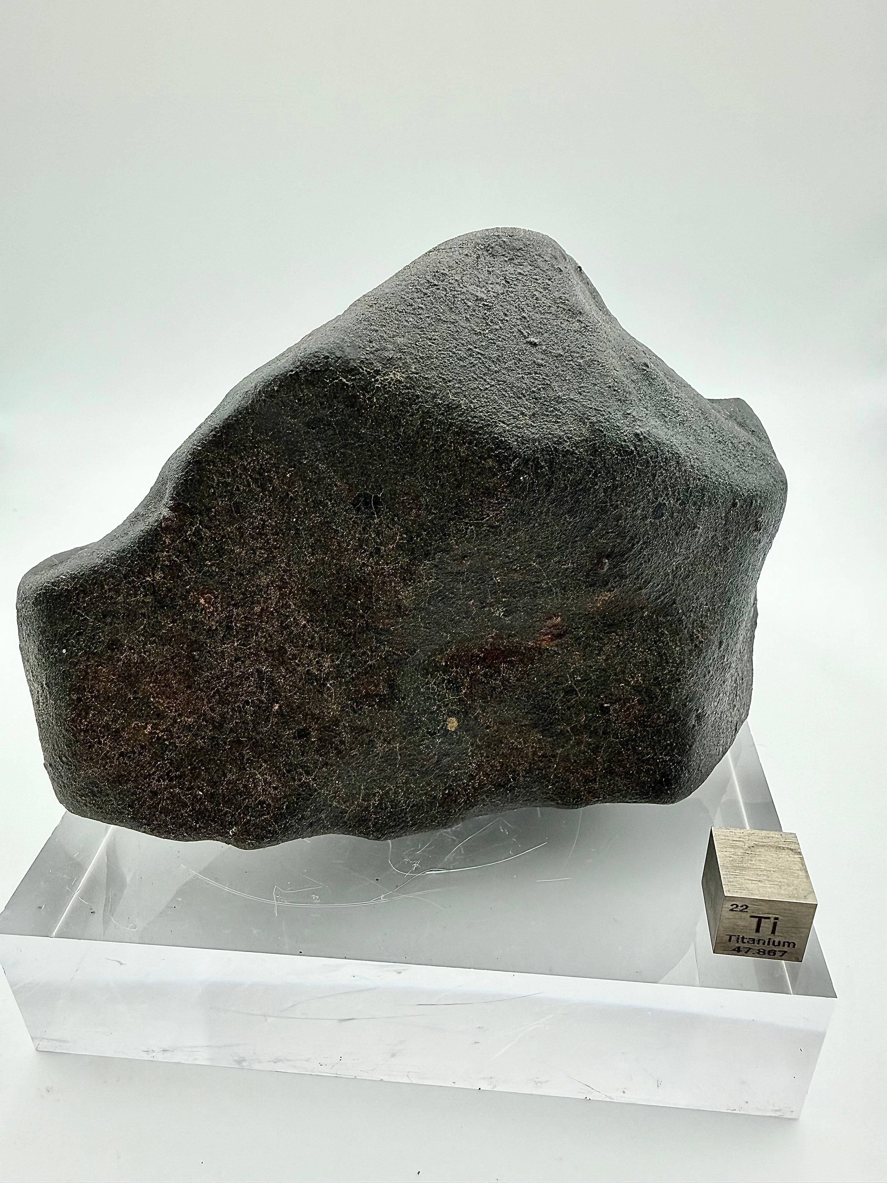 NWA XXX meteorite 820.15g -- fusion crust detail showing glossy black glass coating and thermal stress fractures