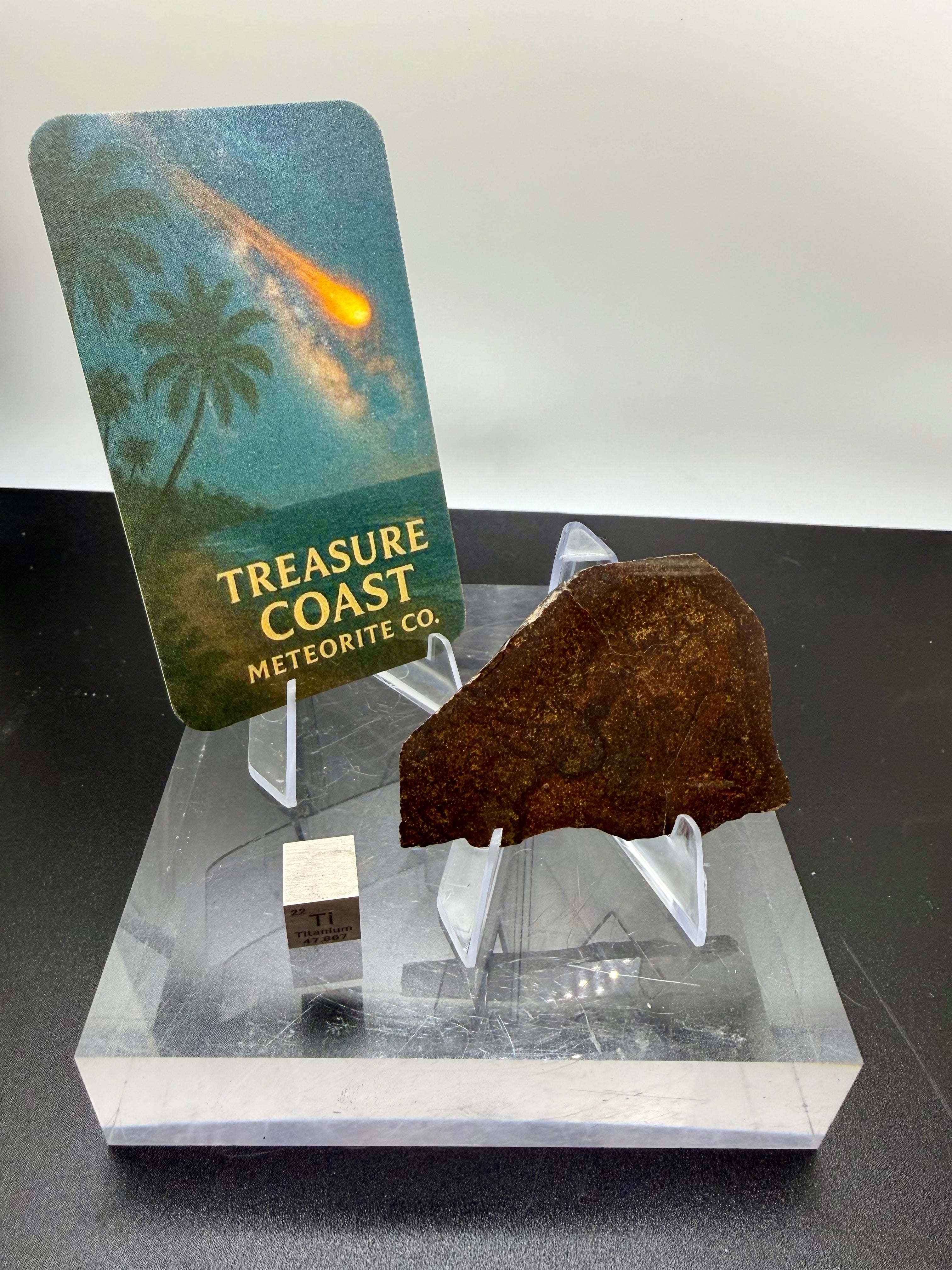 CO3 Meteorite on a display stand with a card labeled 'Treasure Coast Meteorite Co.'