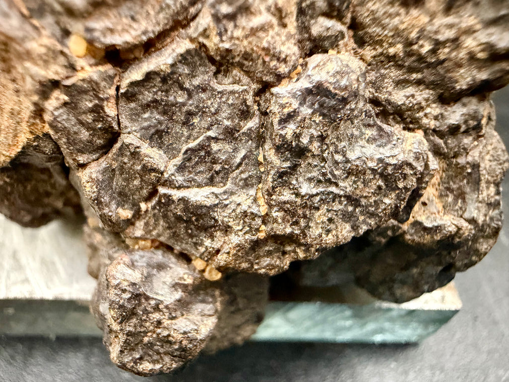 Macro photo of NWA 18592 Mesosiderite Meteorite showing second view of remnant fusion crust zone with glassy surface contrasting weathered stony-iron matrix, 161g