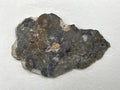 Adrar 013 lunar melt breccia slice, 6.00 g, wide polished face with a tan clast at upper center, a small rough tan patch near center, and fine white veining, on white background