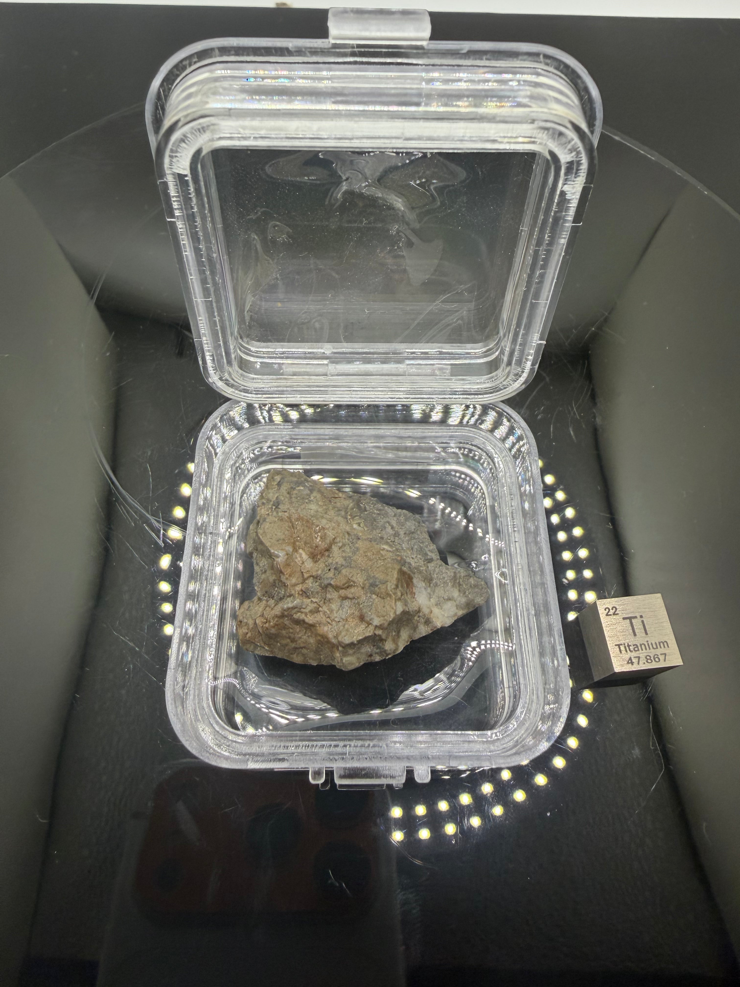 Adrar 013 lunar melt breccia meteorite 14.76g complete individual in display case with titanium element cube for scale, anorthositic norite gabbro composition from the Moon