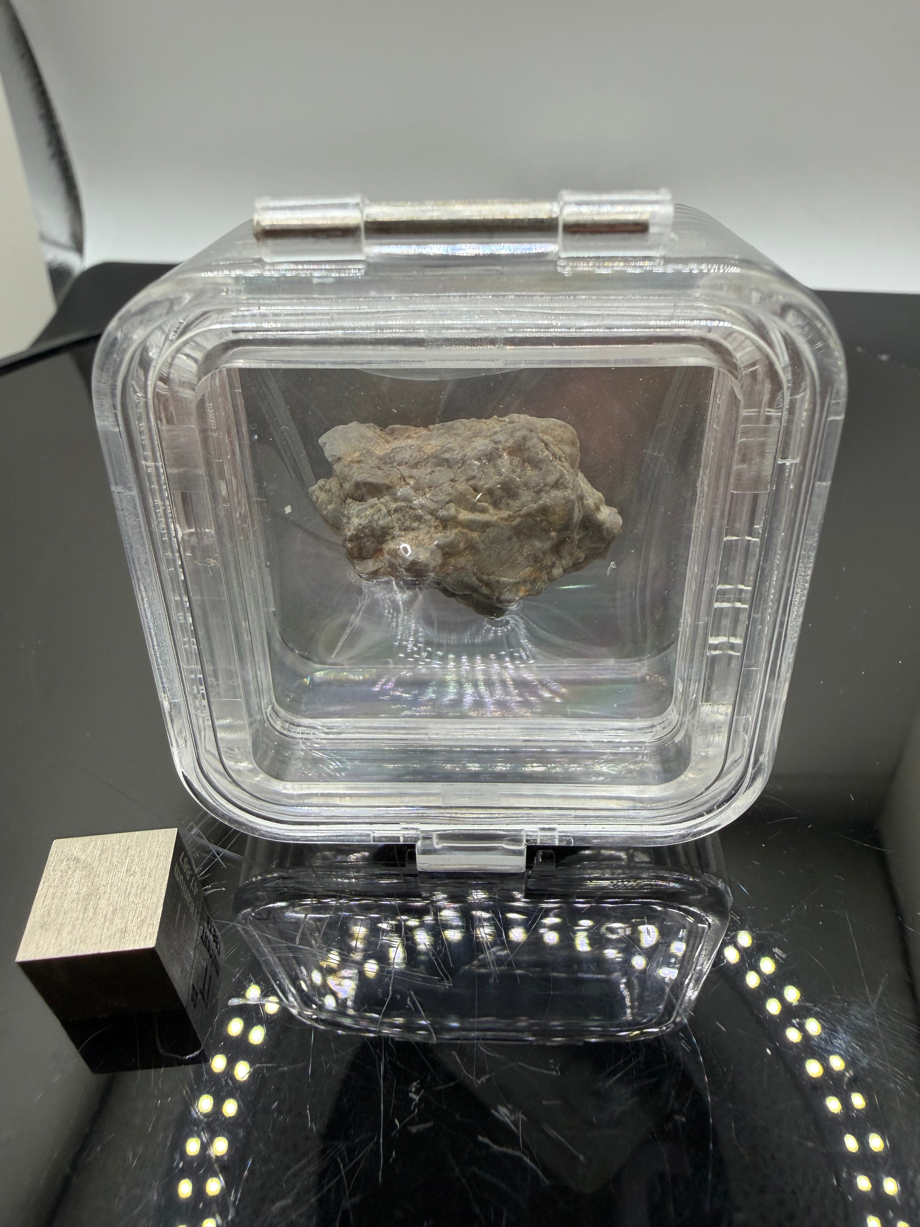 Adrar 013 lunar meteorite 8.08g complete uncut individual in display case with metal scale cube preserving natural impact melt geometry