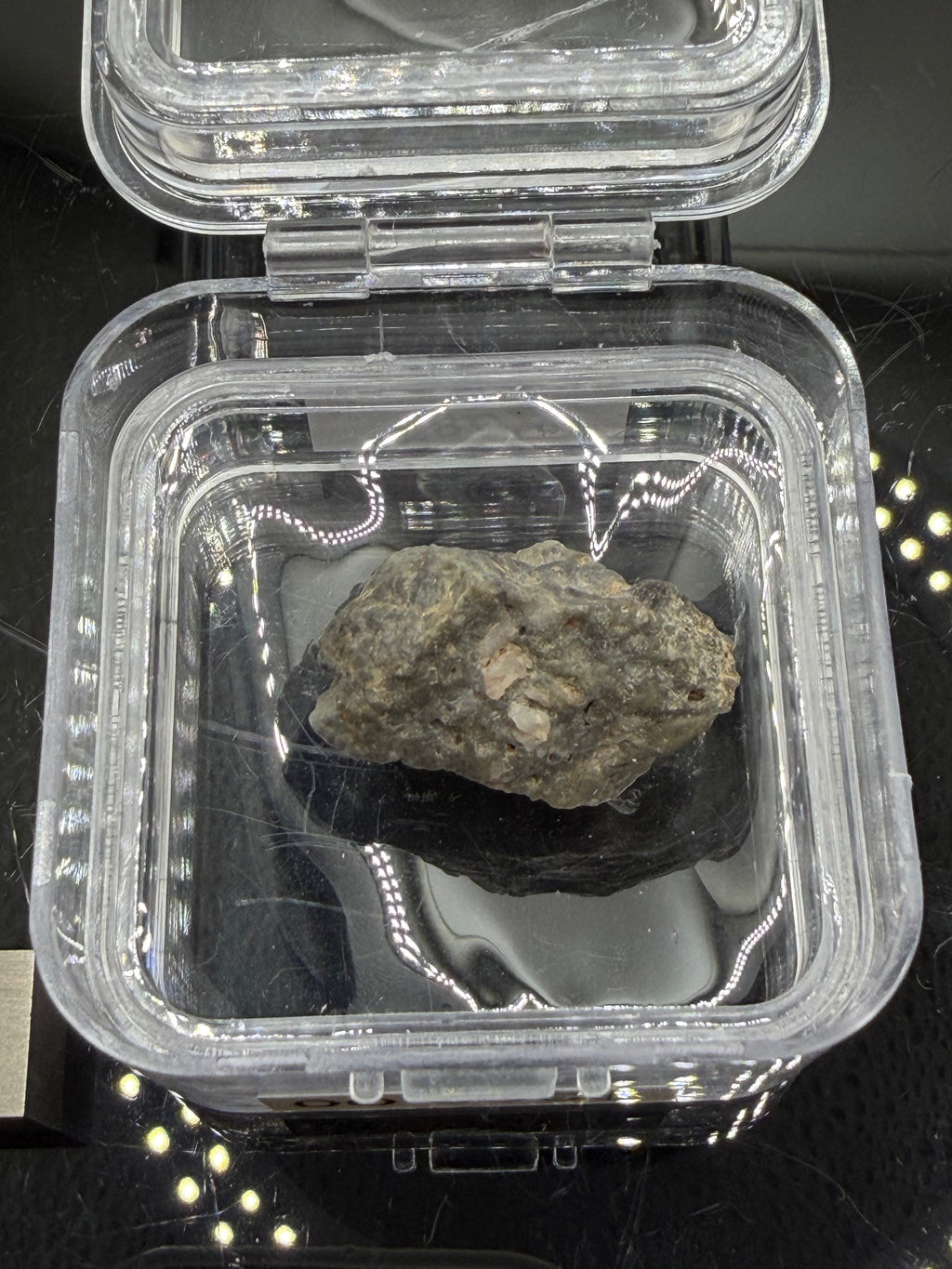 Adrar 013 lunar meteorite 8.08g in open display case showing flow banded impact melt matrix with high relief mineral clasts