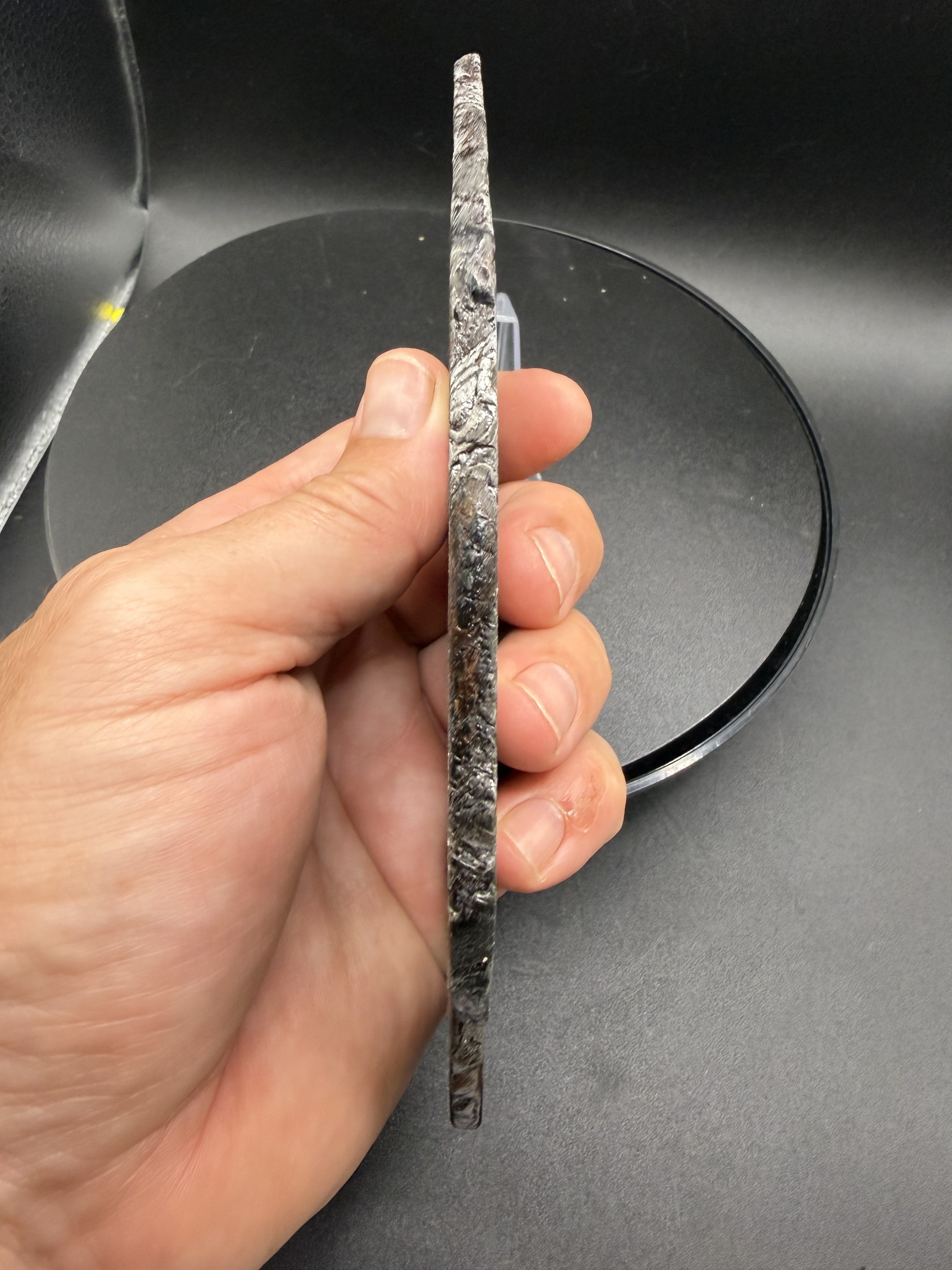 Edge profile of the 334.12g Aletai iron meteorite slice, showing thickness and natural exterior surface