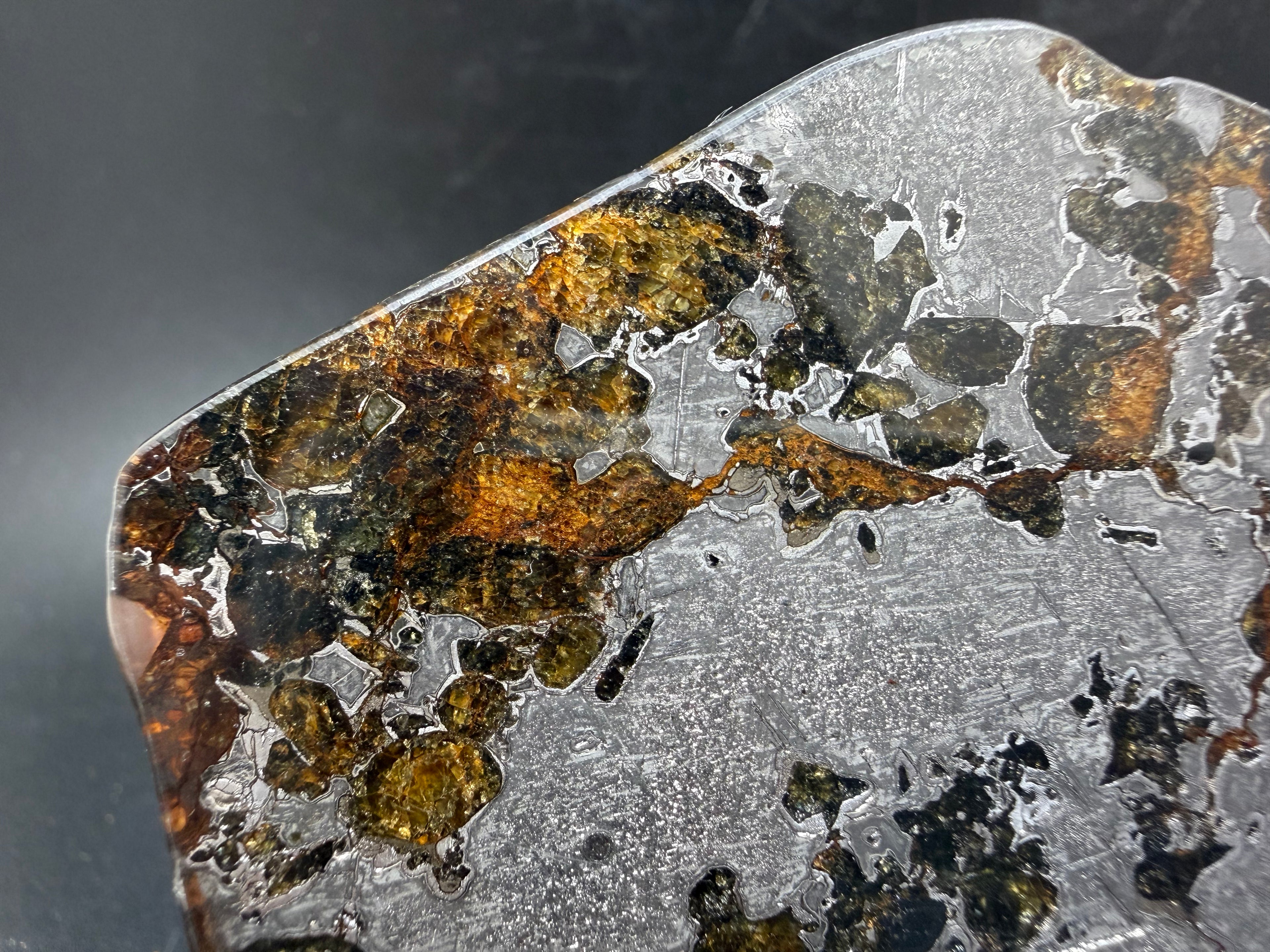 Macro view of Gyarub Zangbo pallasite slice showing large amber olivine cluster with green tones in polished iron-nickel matrix, 54.18g