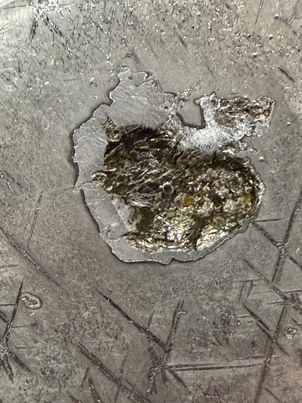 Macro view of a dark inclusion set in etched metal, Gyarub Zangbo pallasite, 324.46g