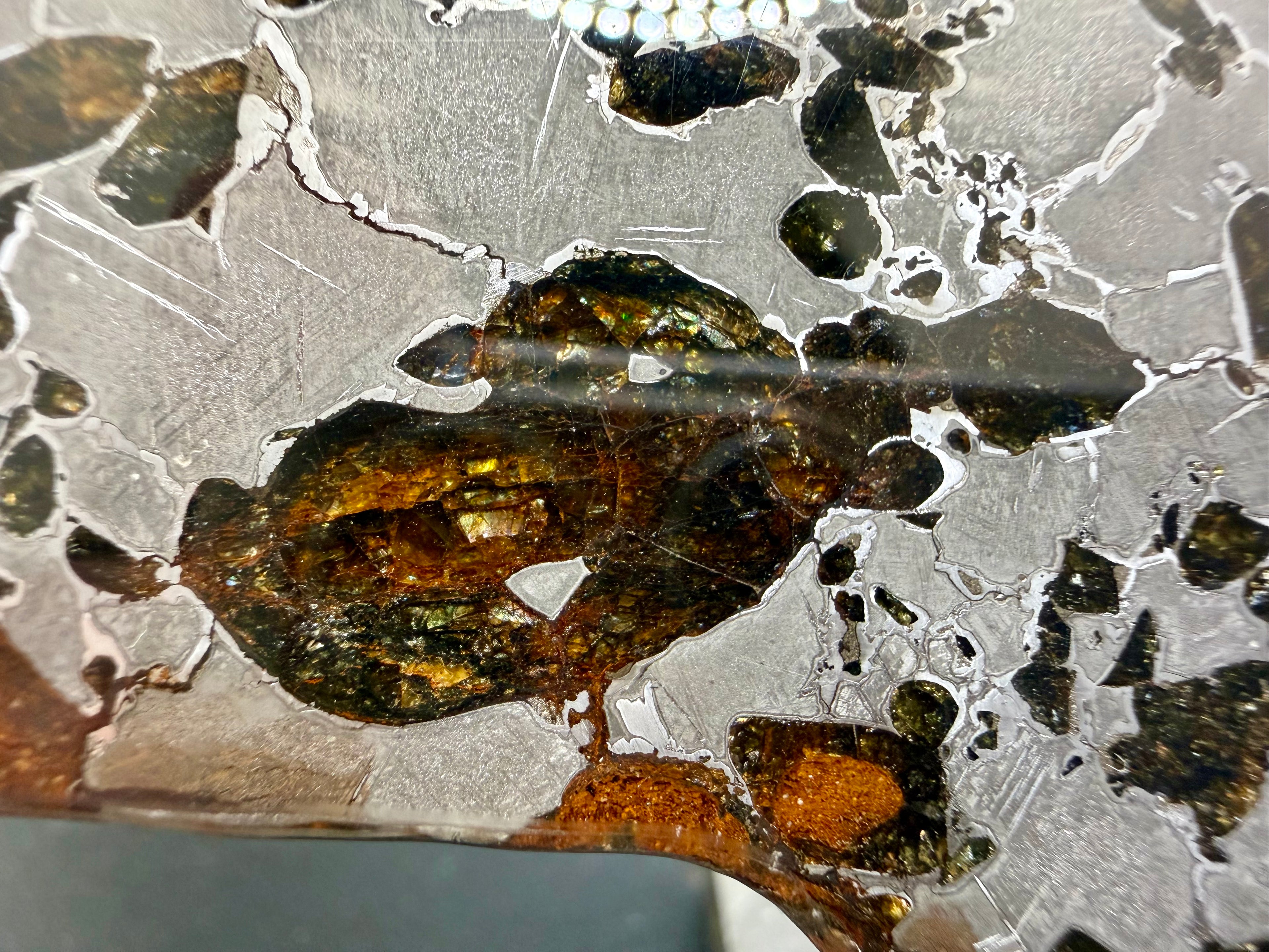 Gyarub Zangbo pallasite 64.00g -- close-up of angular olivine crystals showing green and gold tones with cracked iron-nickel matrix