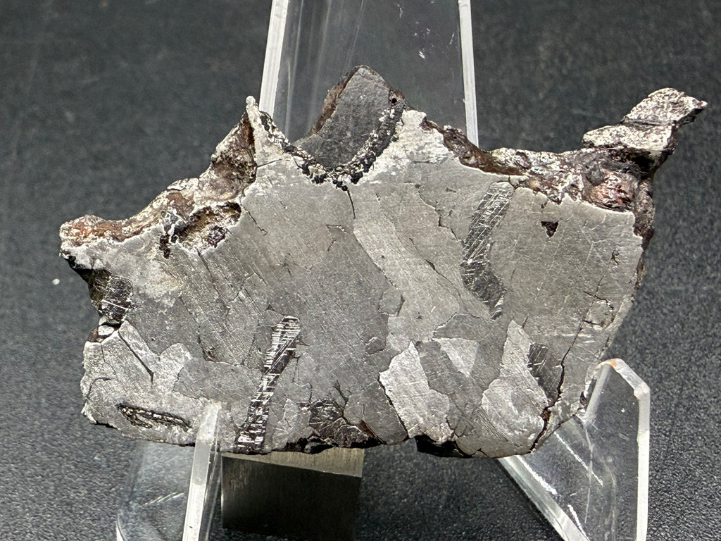 Kaalijarv iron meteorite, IAB-MG, 12.83 g slice standing upright, second face with lighter kamacite areas, narrow dark bands with Neumann lines, and brown weathered metal along the upper edge