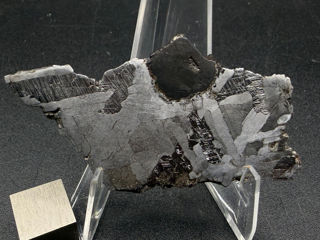 Kaalijarv iron meteorite, IAB-MG, 15.78 g slice, closer view of the etched face with the rounded dark inclusion at the top edge and Neumann bands in the darker zones