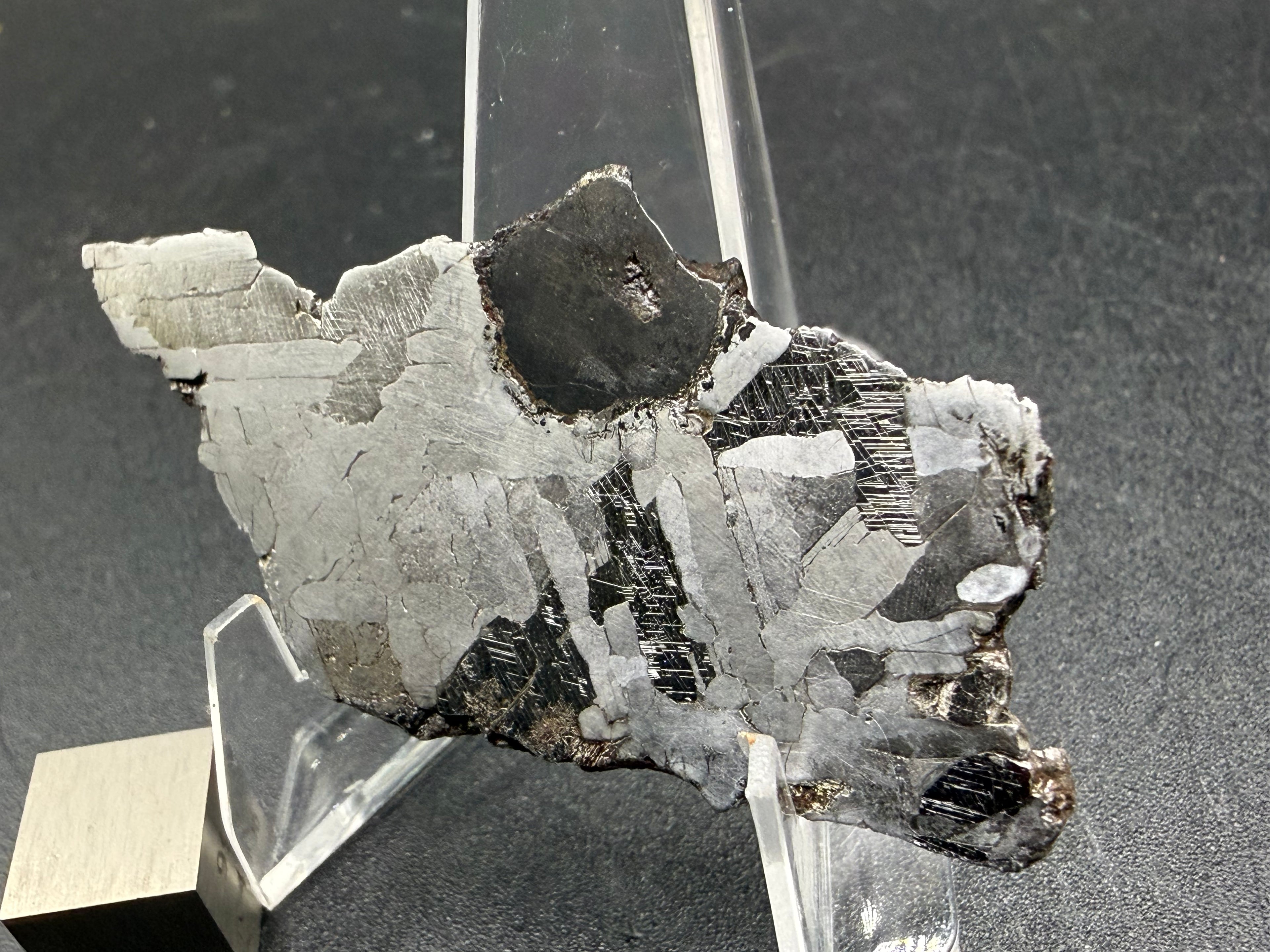 Kaalijarv iron meteorite, IAB-MG, 15.78 g etched slice standing upright, lit from a different angle so lighter and darker zones of the etched metal contrast more strongly