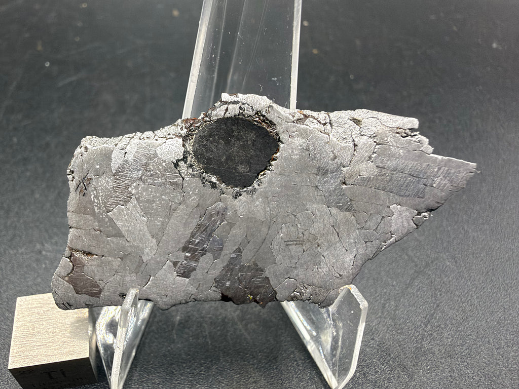 Kaalijarv IAB-MG iron meteorite slice, 17.00 g, closer view of the front face showing the dark dark inclusion and the etched kamacite crystals around it
