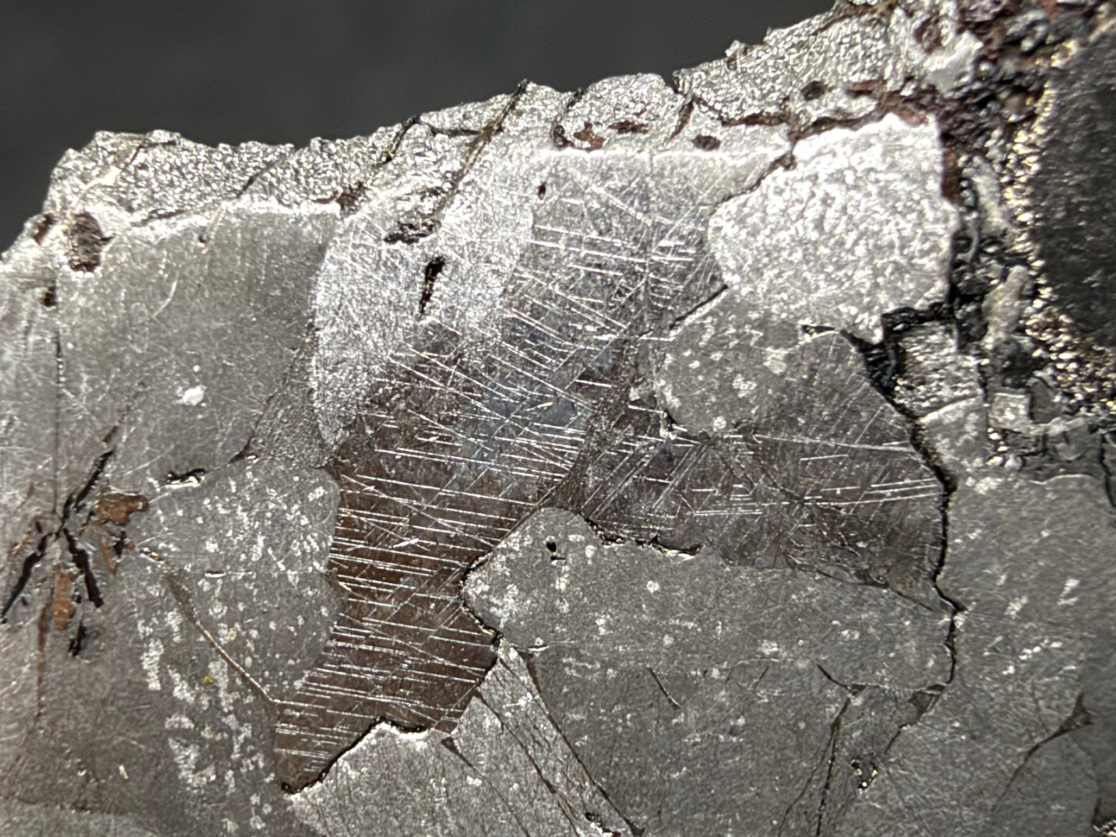 Kaalijarv IAB-MG iron meteorite slice, 17.00 g, close-up of fine parallel Neumann bands crossing kamacite crystals near the top edge