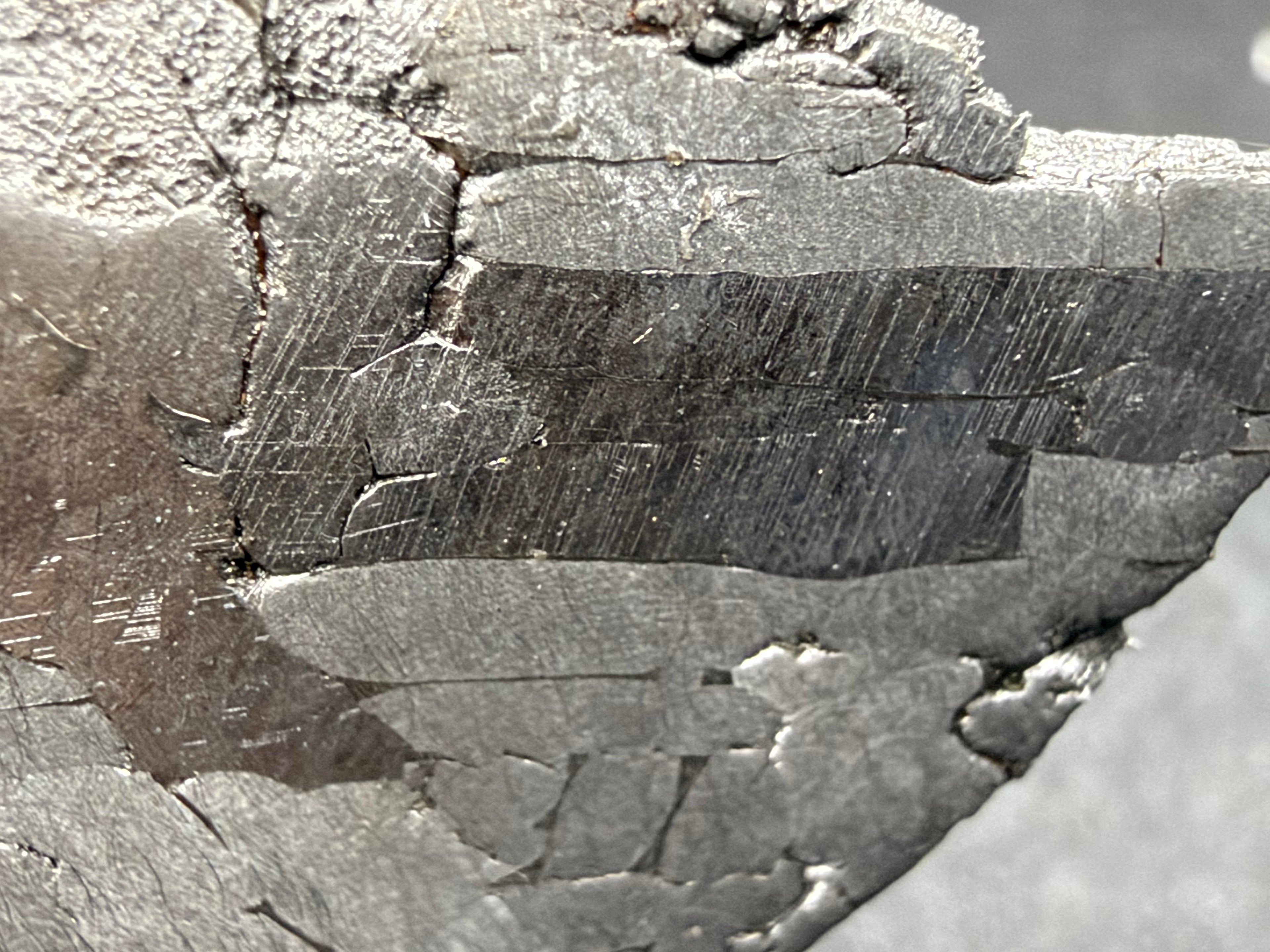 Kaalijarv IAB-MG iron meteorite slice, 17.00 g, close-up of sets of parallel Neumann bands within an elongated kamacite crystal