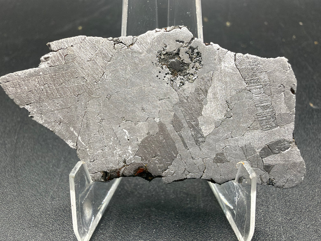 Kaalijarv IAB-MG iron meteorite slice, 17.00 g, reverse face etched, on an acrylic stand, showing the smaller irregular outline of the dark inclusion