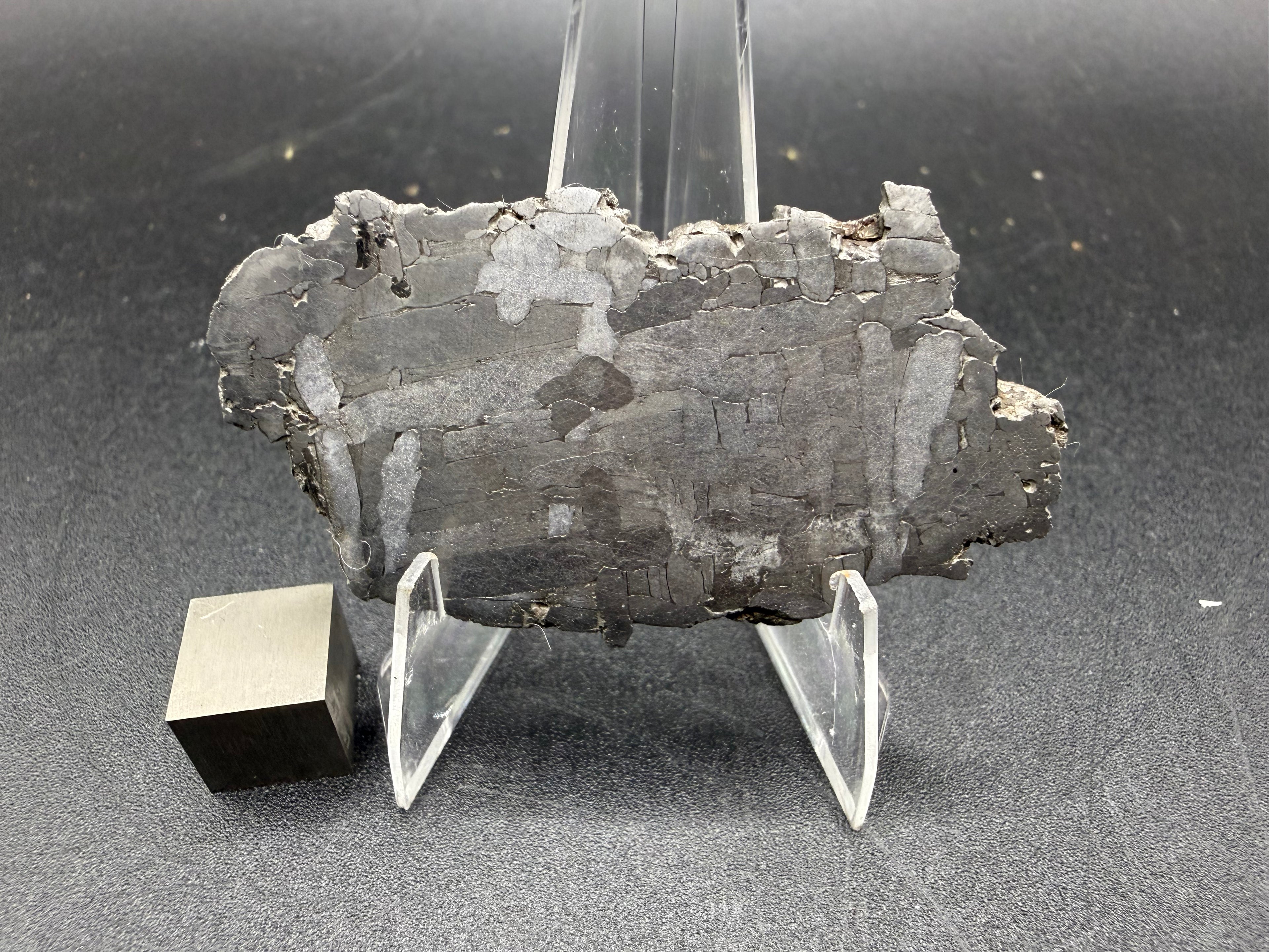 Kaalijarv iron meteorite, IAB-MG, 21.42 g slice on a clear acrylic stand with a scale cube, full view of the etched face showing the Widmanstatten pattern and weathered edges