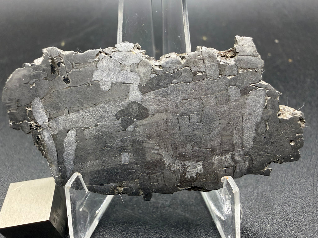Kaalijarv iron meteorite, IAB-MG, 21.42 g slice on a clear acrylic stand with a scale cube, closer view of the etched face showing the Widmanstatten pattern and weathered edges