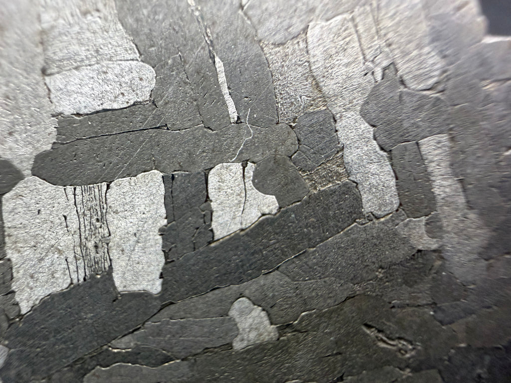 Kaalijarv iron meteorite, IAB-MG, 28.43 g slice, close-up of bright and dark gray kamacite plates crossing at right angles on the etched face
