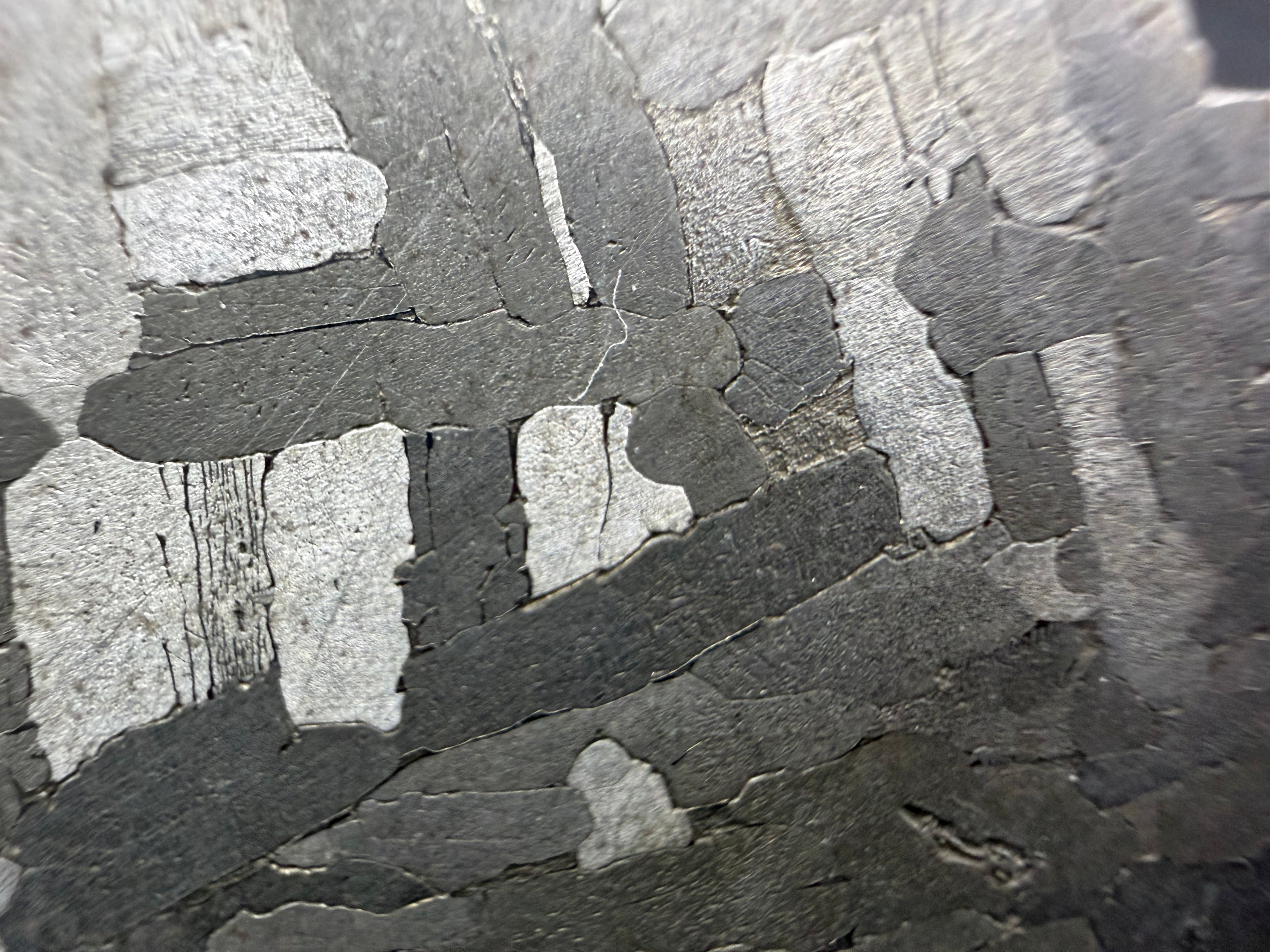 Kaalijarv iron meteorite, IAB-MG, 28.43 g slice, close-up of bright and dark gray kamacite plates crossing at right angles on the etched face