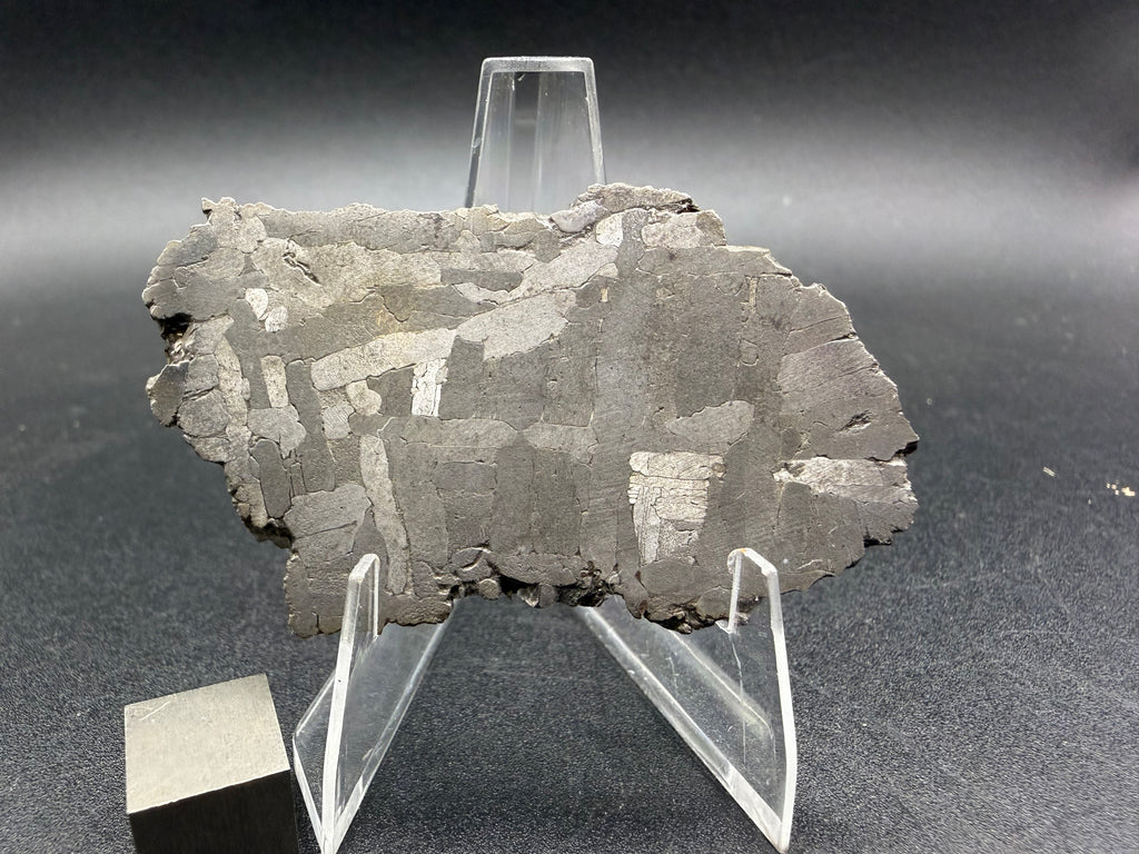 Kaalijarv iron meteorite, IAB-MG, 28.43 g slice standing upright, etched face under bright light with gray kamacite plates and scattered bright plates
