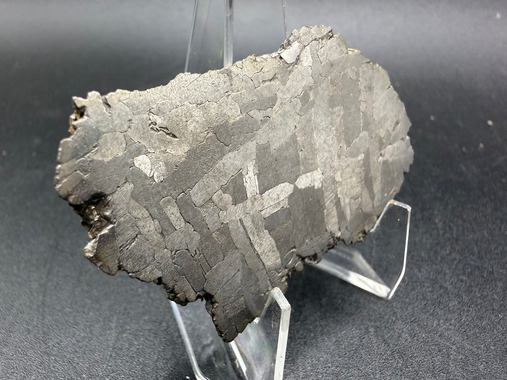 Kaalijarv iron meteorite, IAB-MG, 28.43 g slice lit from the side, etched face with interlocking kamacite plates in several directions