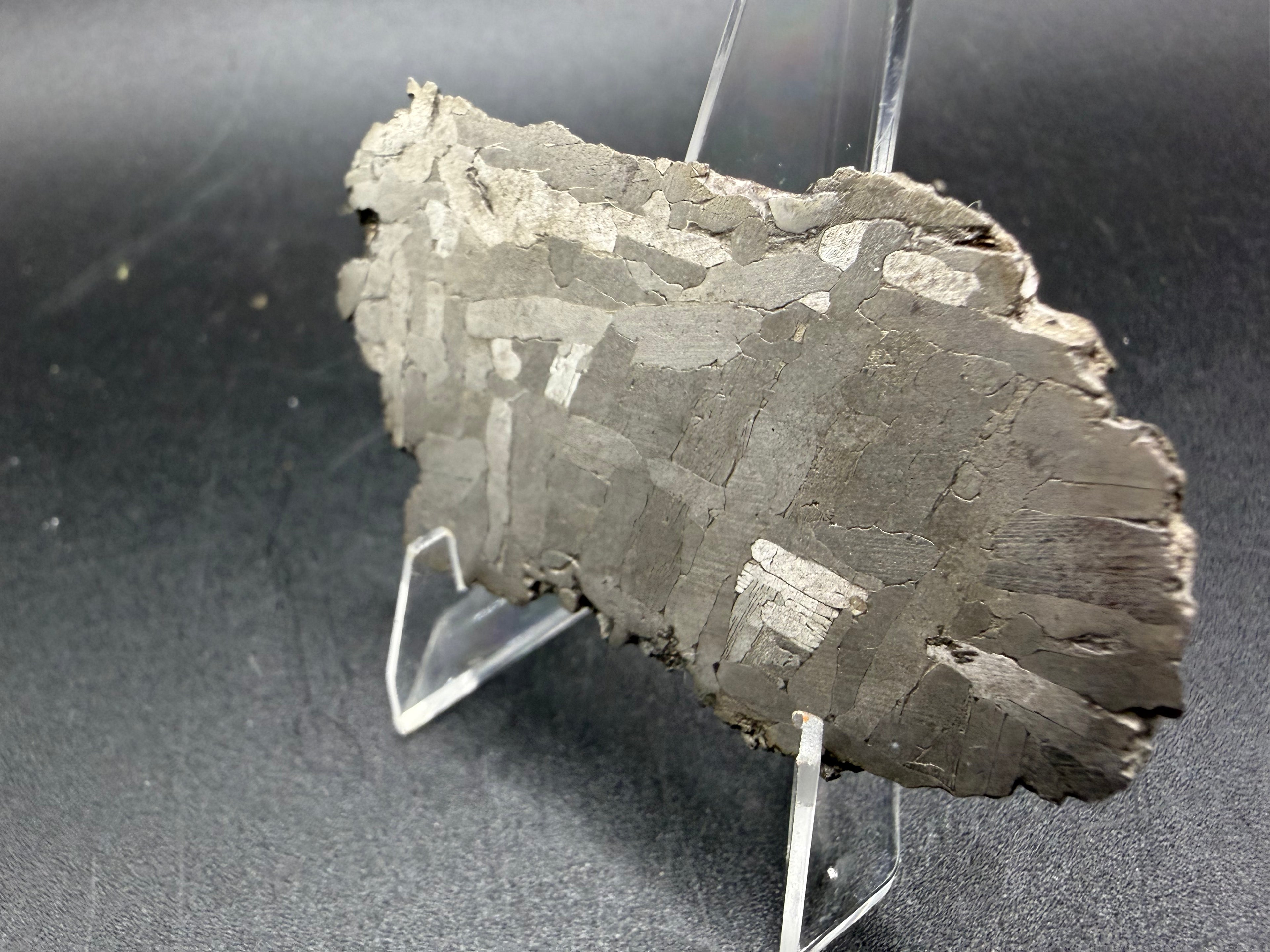 Kaalijarv iron meteorite, IAB-MG, 28.43 g slice seen at an angle, etched face with gray kamacite plates crossing and a few bright plates