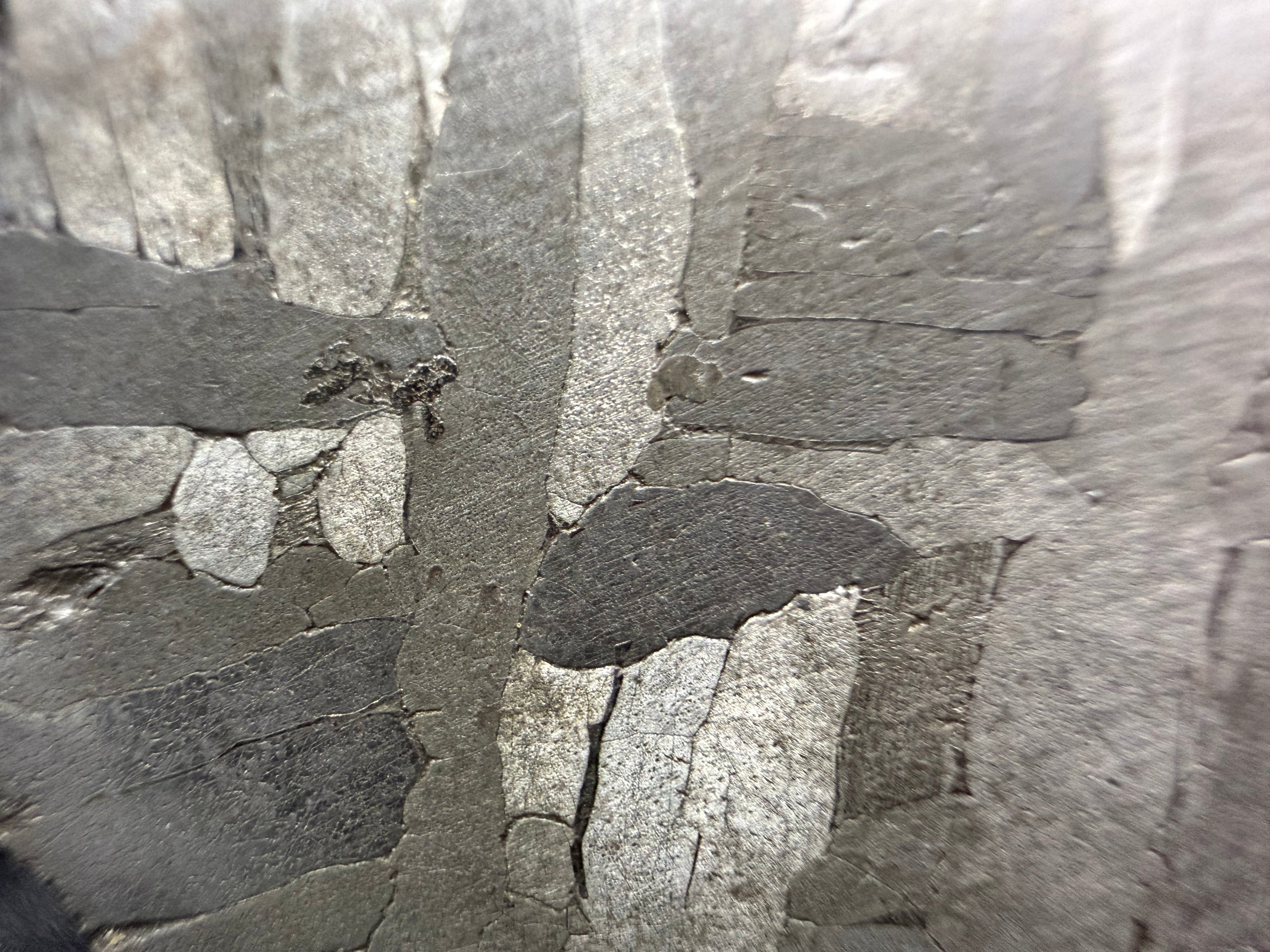 Kaalijarv iron meteorite, IAB-MG, 28.43 g slice, close-up of the etched face with crossing kamacite plates in light and dark gray and a small dark pocket at left