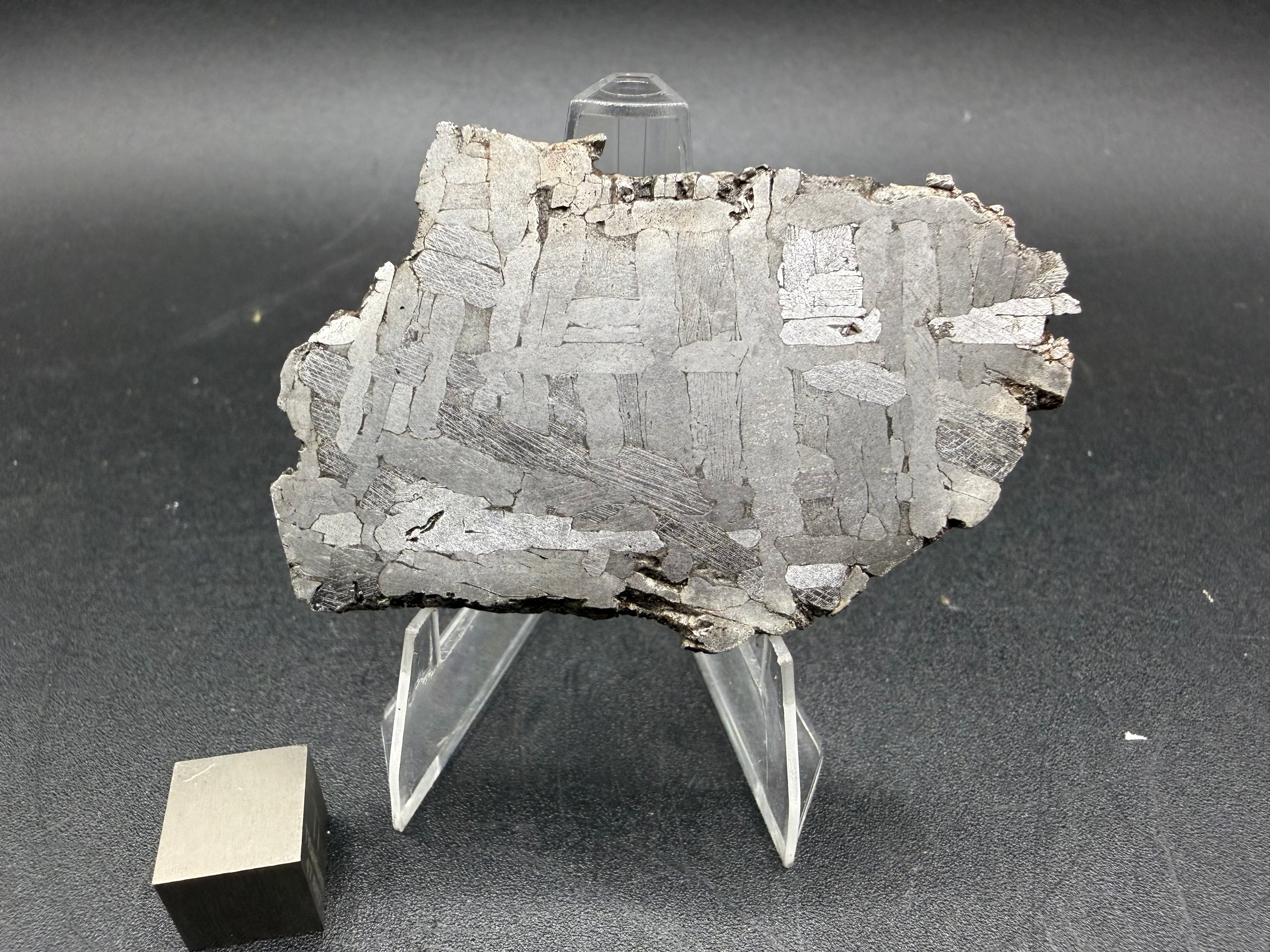 Kaalijarv iron meteorite, IAB-MG, 30.35 g slice on a clear acrylic stand with a scale cube, full view of the etched face showing crossing Widmanstatten plates