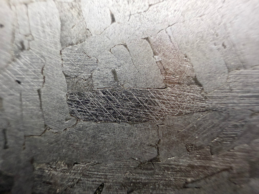 Kaalijarv iron meteorite, IAB-MG, 30.35 g slice, close-up of the etched face showing a darker plate crossed by intersecting sets of fine straight Neumann bands