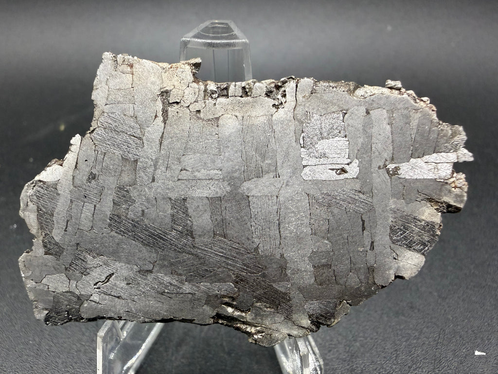 Kaalijarv iron meteorite, IAB-MG, 30.35 g slice on a clear acrylic stand, closer view of the etched face showing crossing Widmanstatten plates, with fine Neumann bands visible in the darker plates
