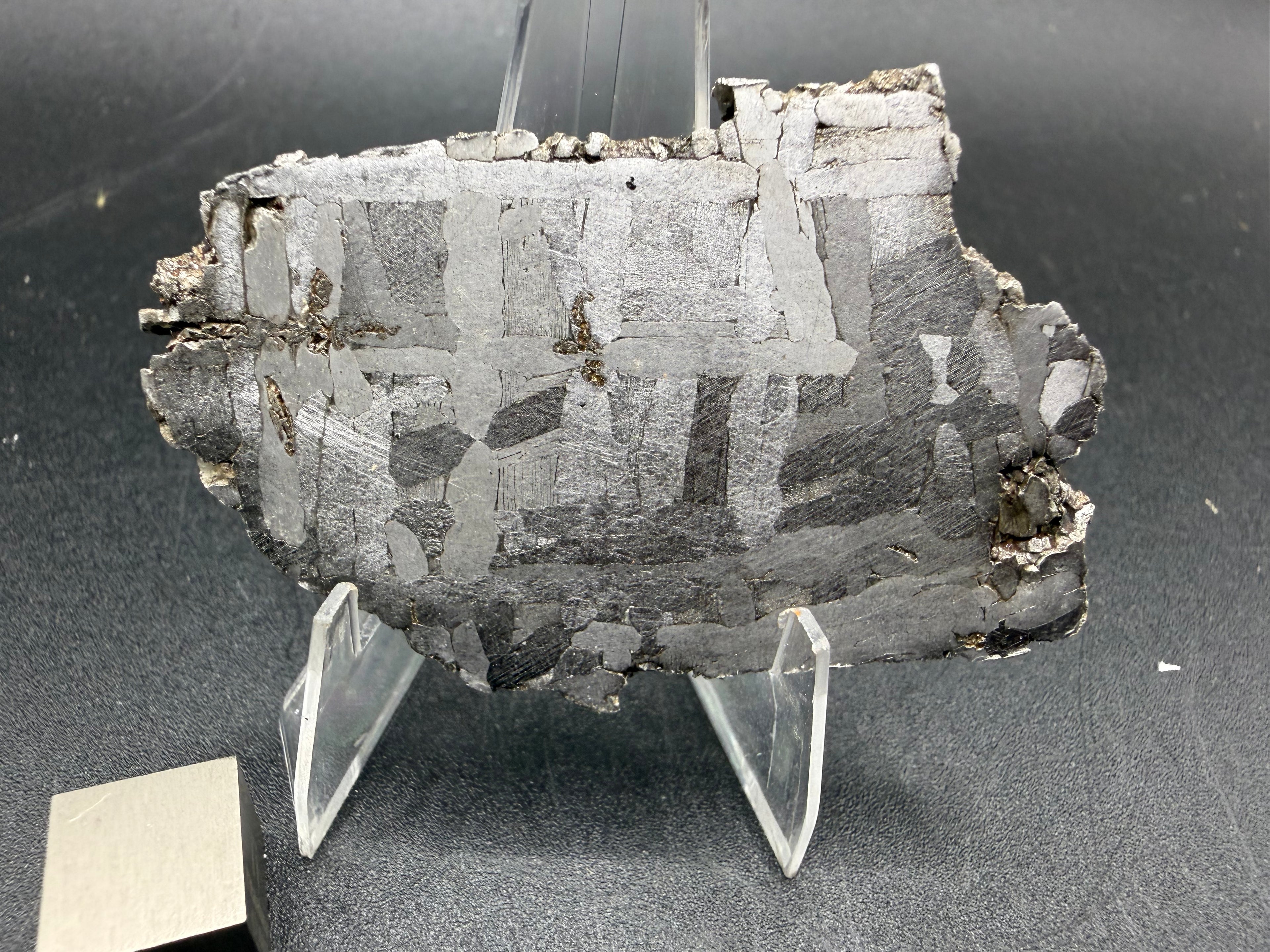 Kaalijarv iron meteorite, IAB-MG, 30.35 g slice on a clear acrylic stand with a scale cube, reverse etched face showing crossing Widmanstatten plates and weathered edges