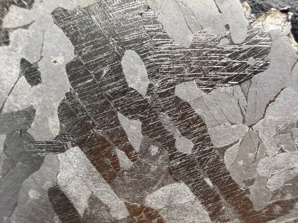 Kaalijarv iron meteorite, IAB-MG, 33.88 g slice, close-up of the etched face with dense intersecting Neumann bands in the darker zones between lighter kamacite areas
