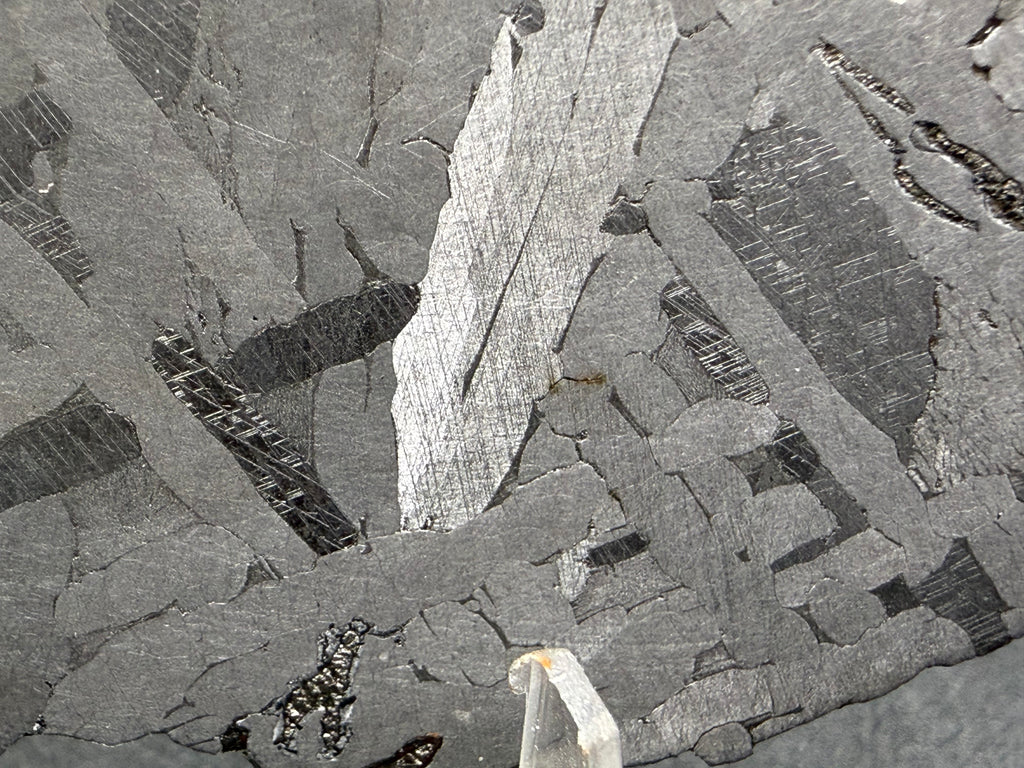 Kaalijarv iron meteorite, IAB-MG, 39.28 g slice, close-up of the etched face with crossing kamacite plates, a bright plate at center, and darker zones crossed by Neumann bands