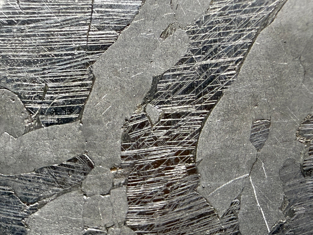 Kaalijarv iron meteorite, IAB-MG, 40.40 g slice, close-up of the etched face showing several intersecting sets of Neumann bands in the darker zones