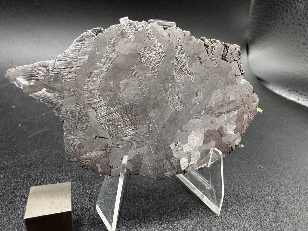 Kaalijarv iron meteorite, IAB-MG, 40.40 g slice standing upright, etched face in softer light with Neumann bands visible across the darker zones
