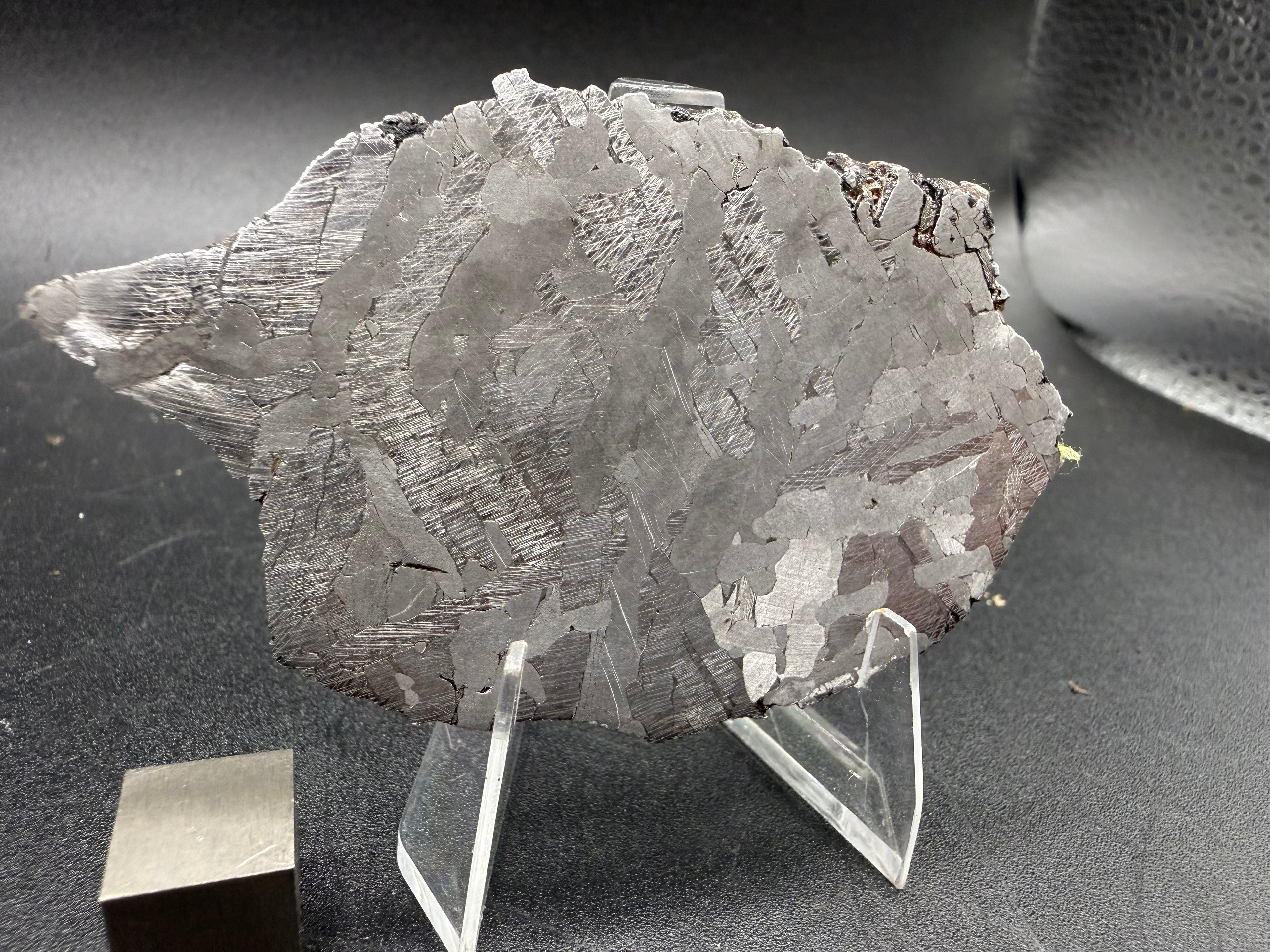Kaalijarv iron meteorite, IAB-MG, 40.40 g slice standing upright, etched face in softer light with Neumann bands visible across the darker zones