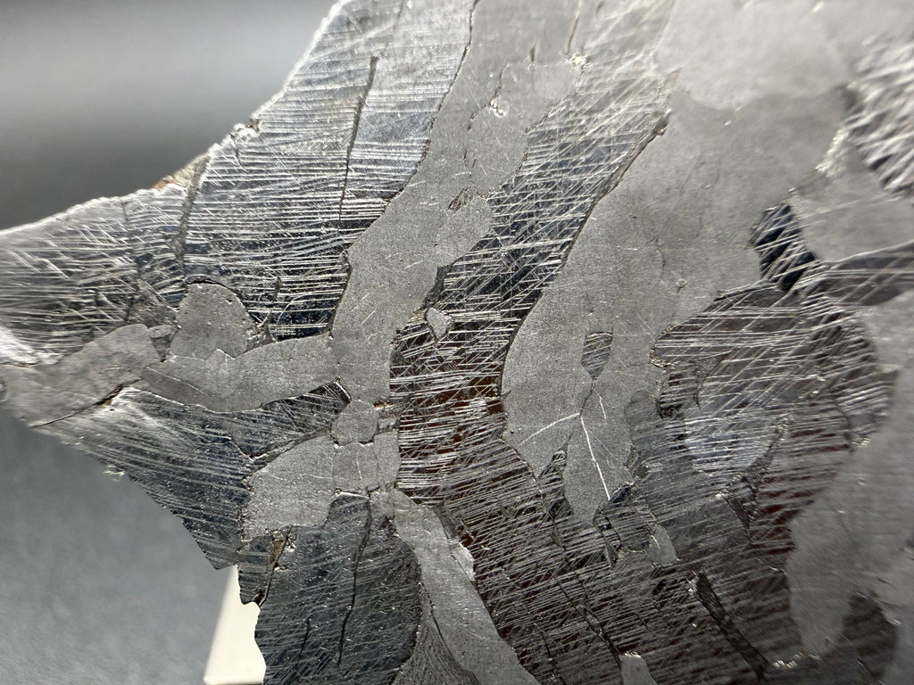 Kaalijarv iron meteorite, IAB-MG, 40.40 g slice, close-up near the edge of the etched face showing dense parallel and intersecting Neumann bands