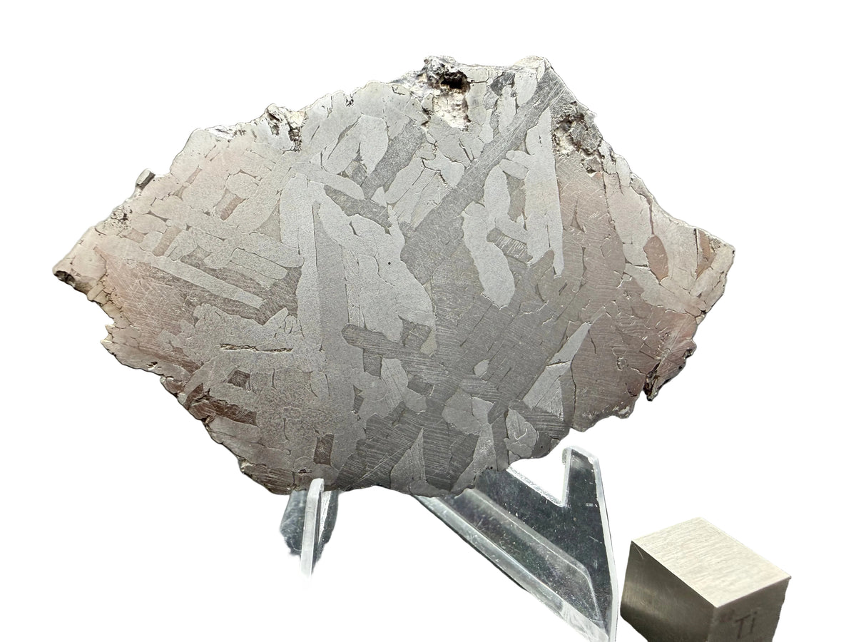 Kaalijarv iron meteorite, IAB-MG, 45.71 g slice on a clear acrylic stand with a scale cube against a white background, etched face showing crossing Widmanstatten plates