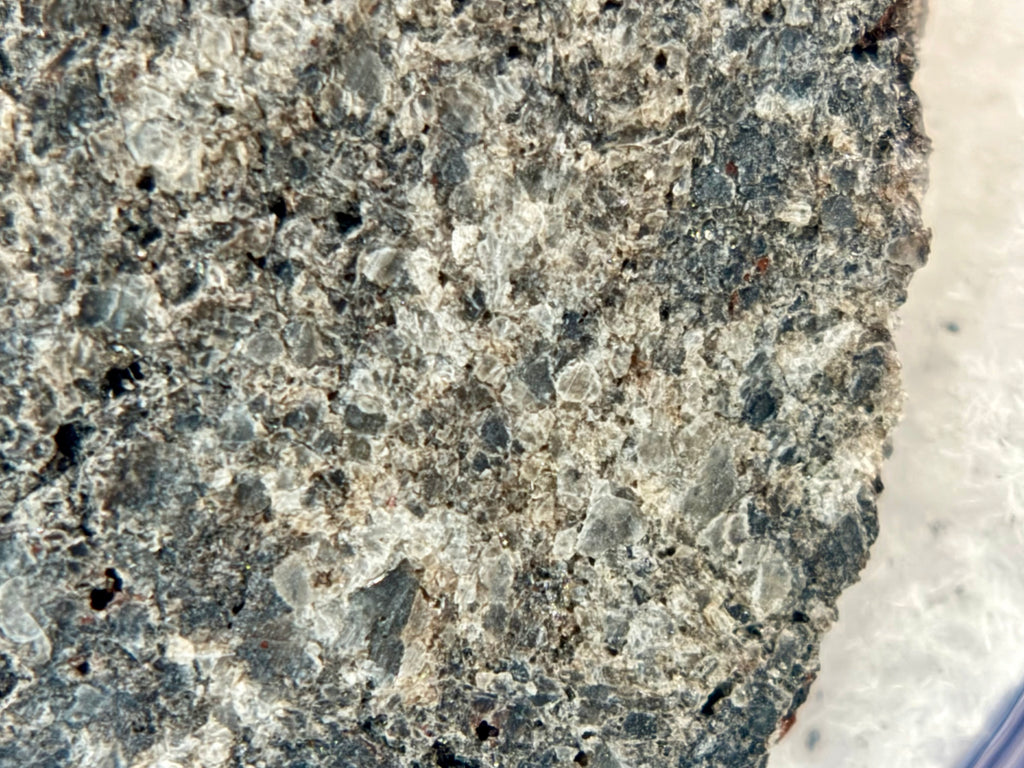 Macro detail of Ksar Ghilane 022 ungrouped achondrite meteorite slice showing internal crystalline structure and pyroxene grain texture, 2.33g
