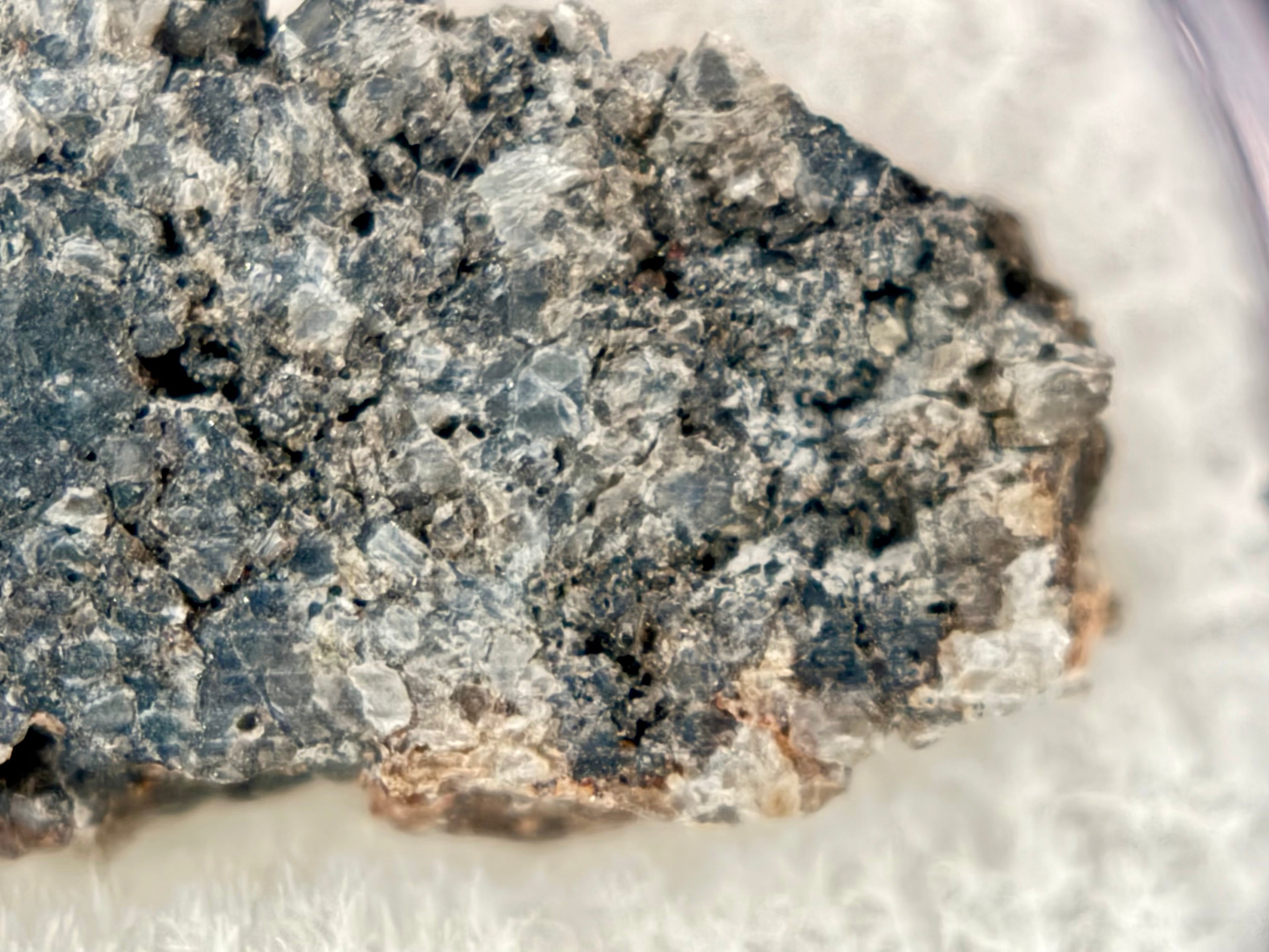 Closeup of Ksar Ghilane 022 ungrouped achondrite meteorite slice showing granular fabric with 1.5 mm augite crystals and sulfide inclusions, 1.75g