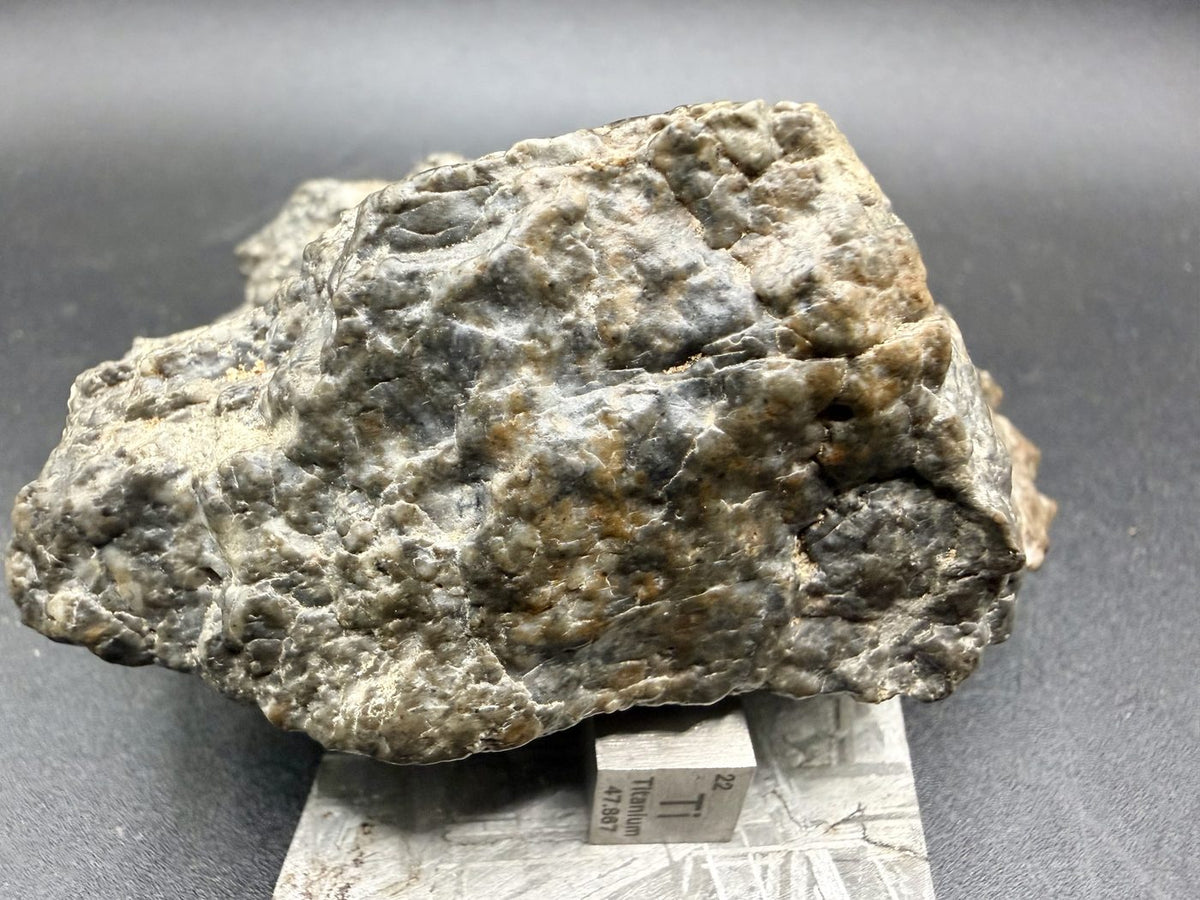 Irregular reverse side of the Laayoune 002 lunar meteorite beside a scale cube