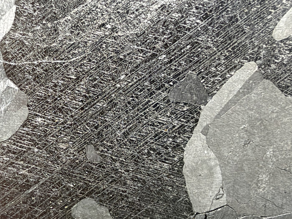 Mount Dooling iron meteorite, IC, 105.76 g slice, close-up of a dark grain on the etched face crossed by dense intersecting sets of fine straight Neumann bands