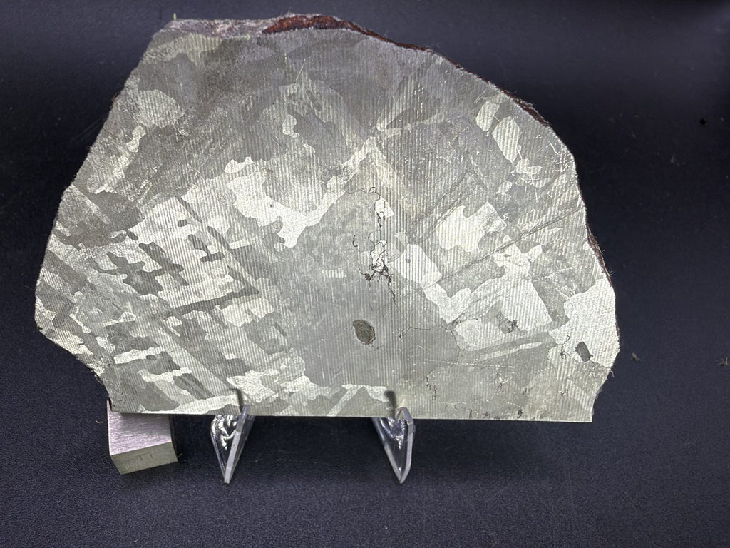Mount Dooling iron meteorite, IC, 105.76 g slice on a clear acrylic stand with a scale cube, reverse wire sawn and etched face showing the crossing plate pattern and the small exit of the dark inclusion