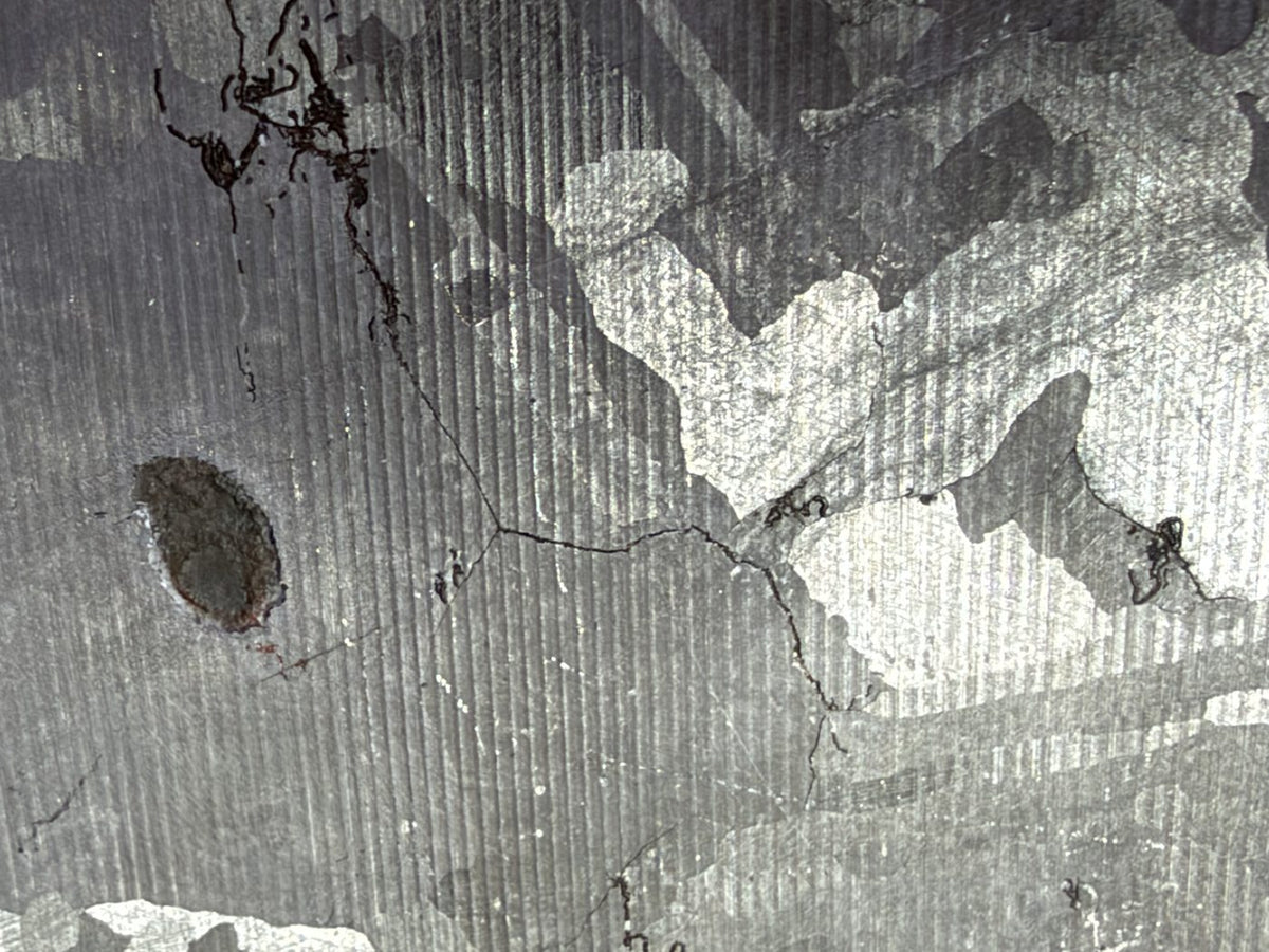 Mount Dooling iron meteorite, IC, 105.76 g slice, close-up of the reverse wire sawn and etched face showing fine saw lines over the etched pattern beside the dark inclusion