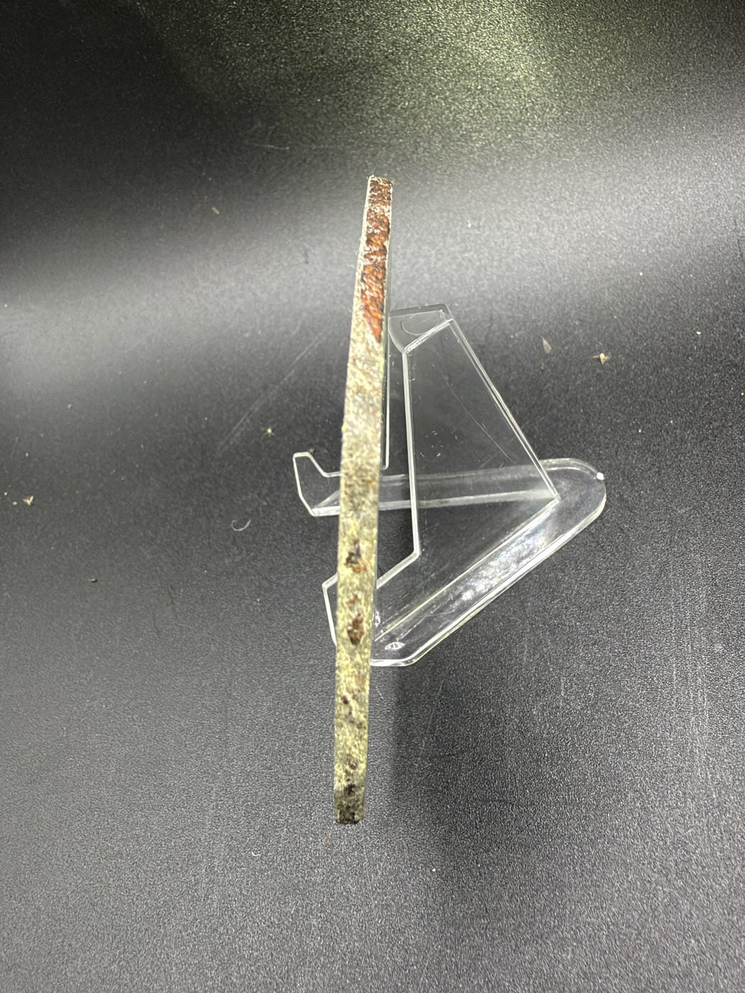 Mount Dooling iron meteorite, IC, 105.76 g slice standing on edge on a clear acrylic stand, showing slice thickness and brown terrestrial oxide along the outer edge