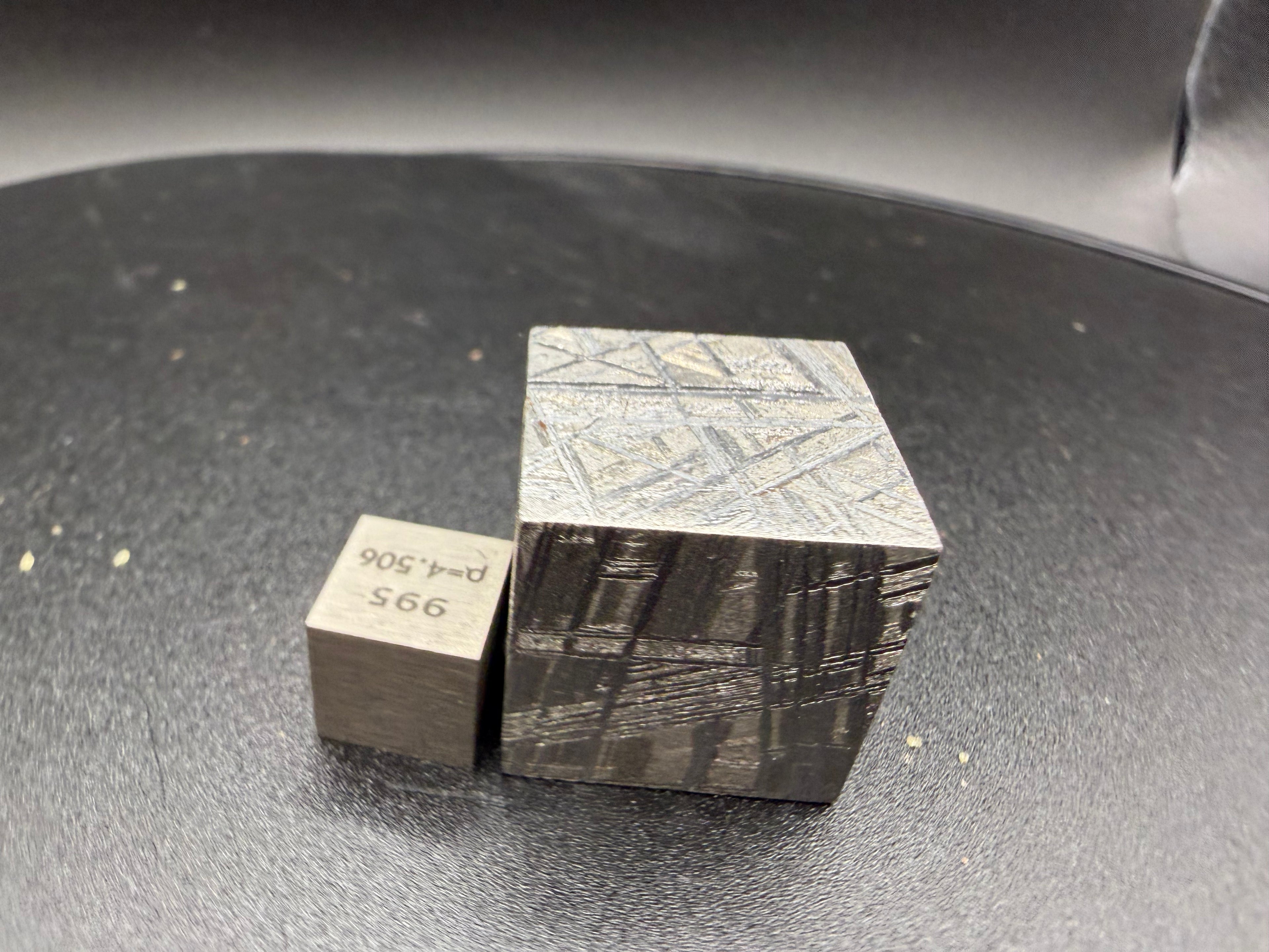 Front view of Muonionalusta iron meteorite 2cm cube showing band orientation shift between faces, with scale cube, 65g