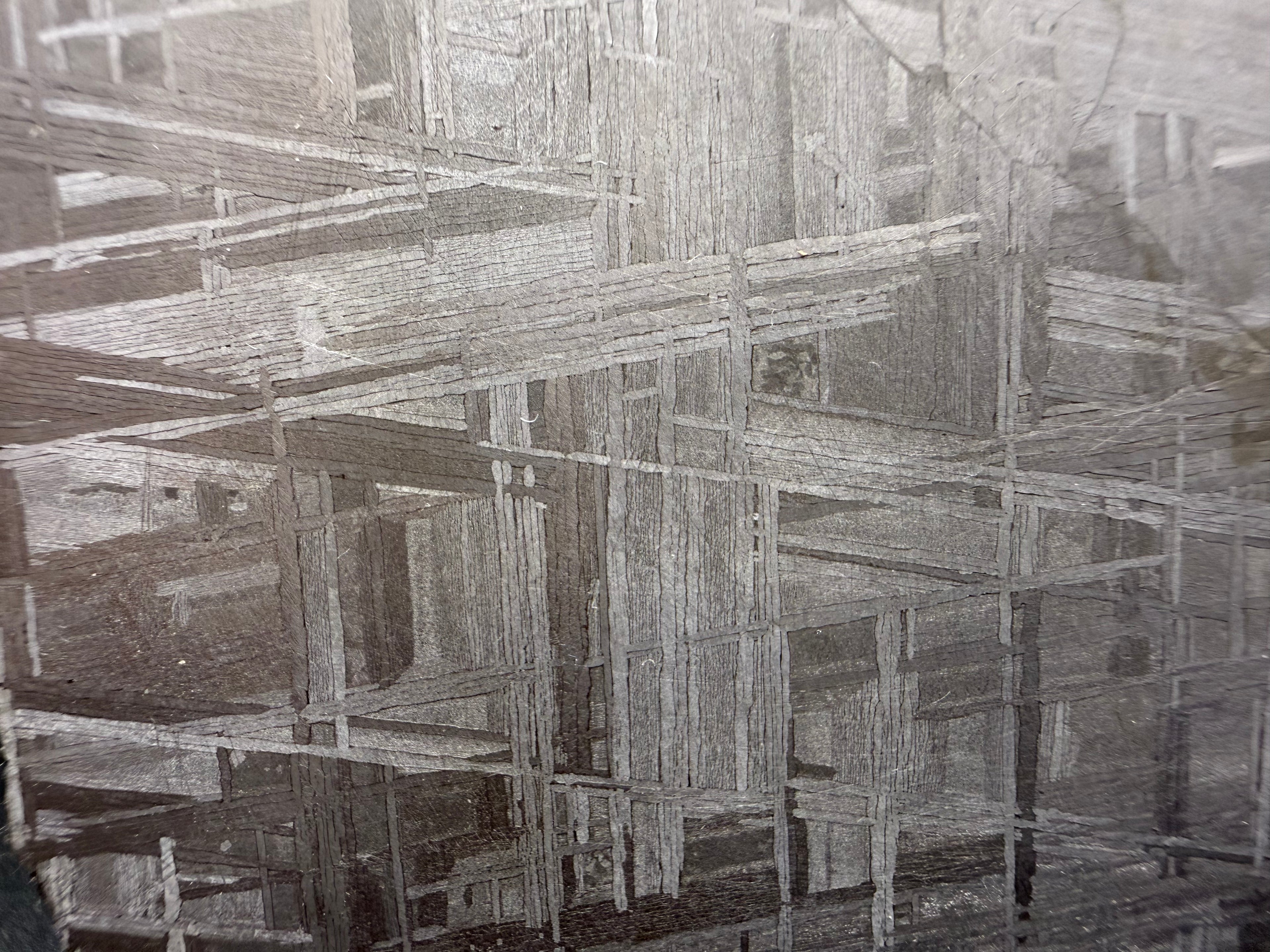 Muonionalusta meteorite close-up showing deformation vein cutting across Widmanstätten pattern in the iron structure.